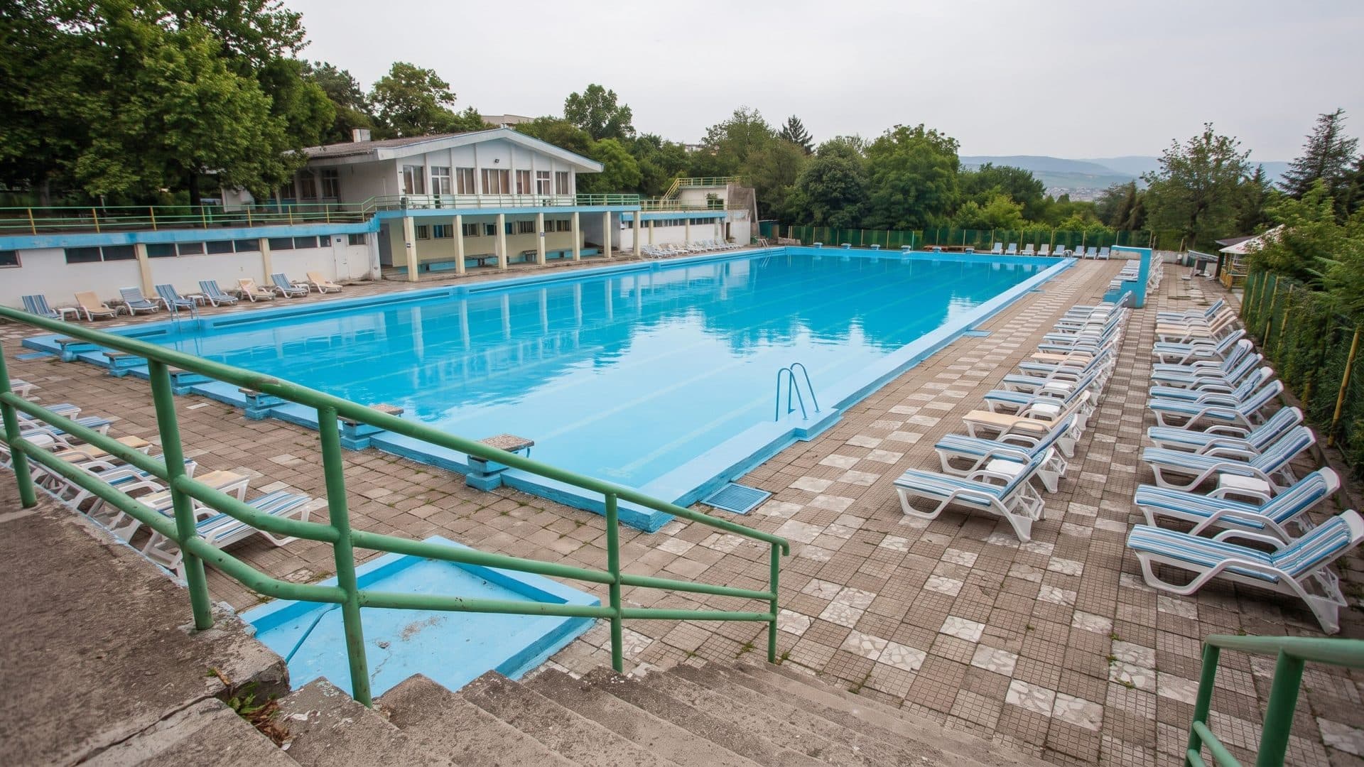 The long outdoor pool at Sun City in Sandanski seen from its far end, loungers in a row along the water