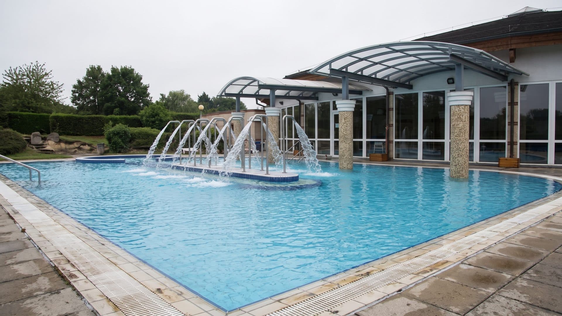 The outdoor pool at the Szilva thermal bath, with its row of water jets under a glazed canopy