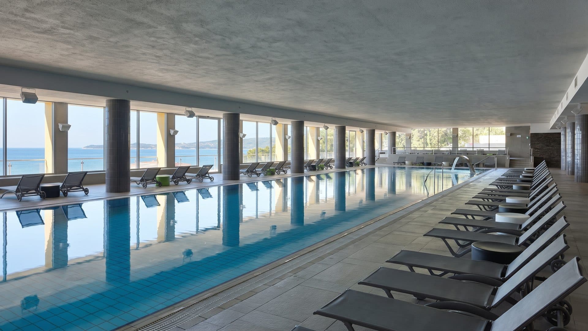 The indoor pool of Talaso Strunjan with loungers along the glazed wall above the sea