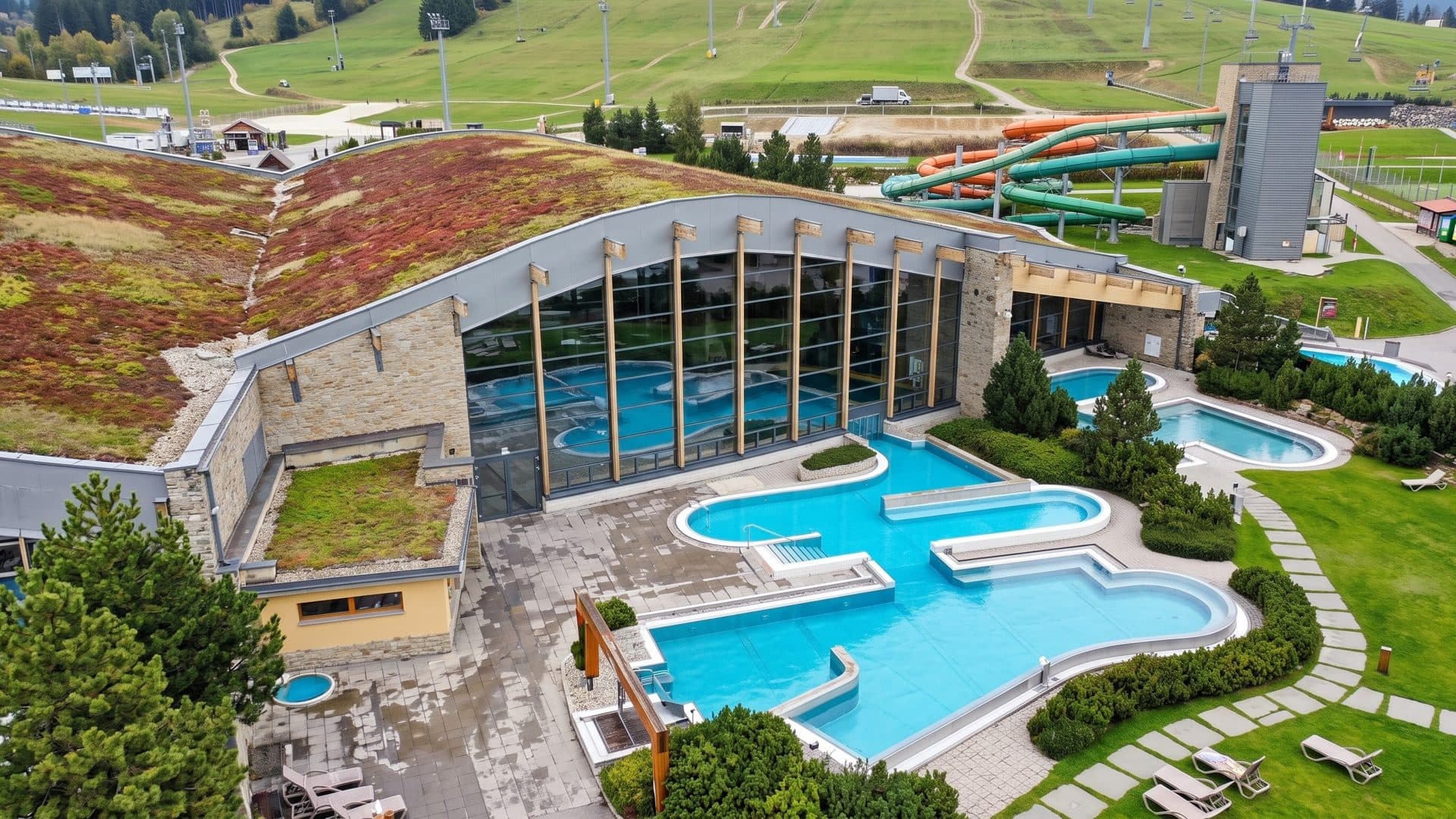 Aerial view of Terma Bania in Bialka Tatrzanska: outdoor pools beside the building with its green grass roof