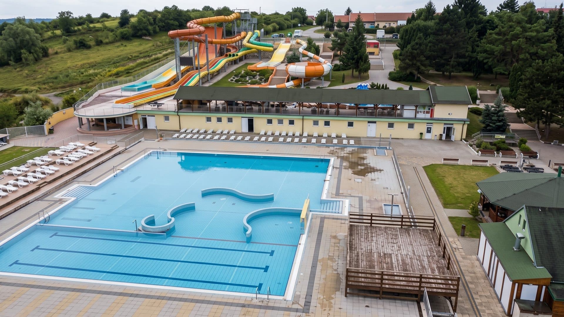 The outdoor thermal pool of Pazit seen from above, with loungers along it and water slides behind