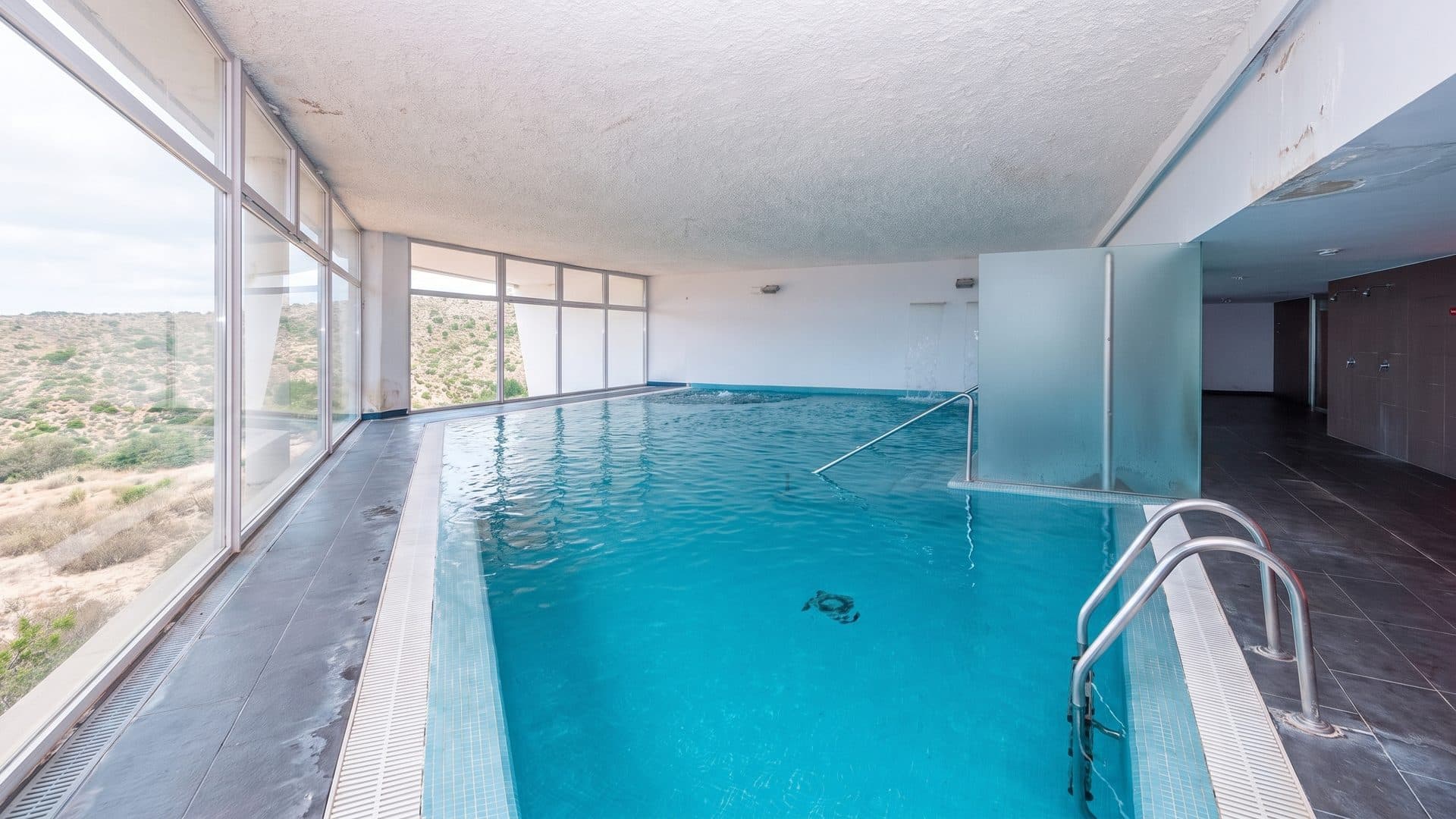 The thermal pool at Termas da Fonte Santa de Almeida seen diagonally from its corner, the tall windows along one side