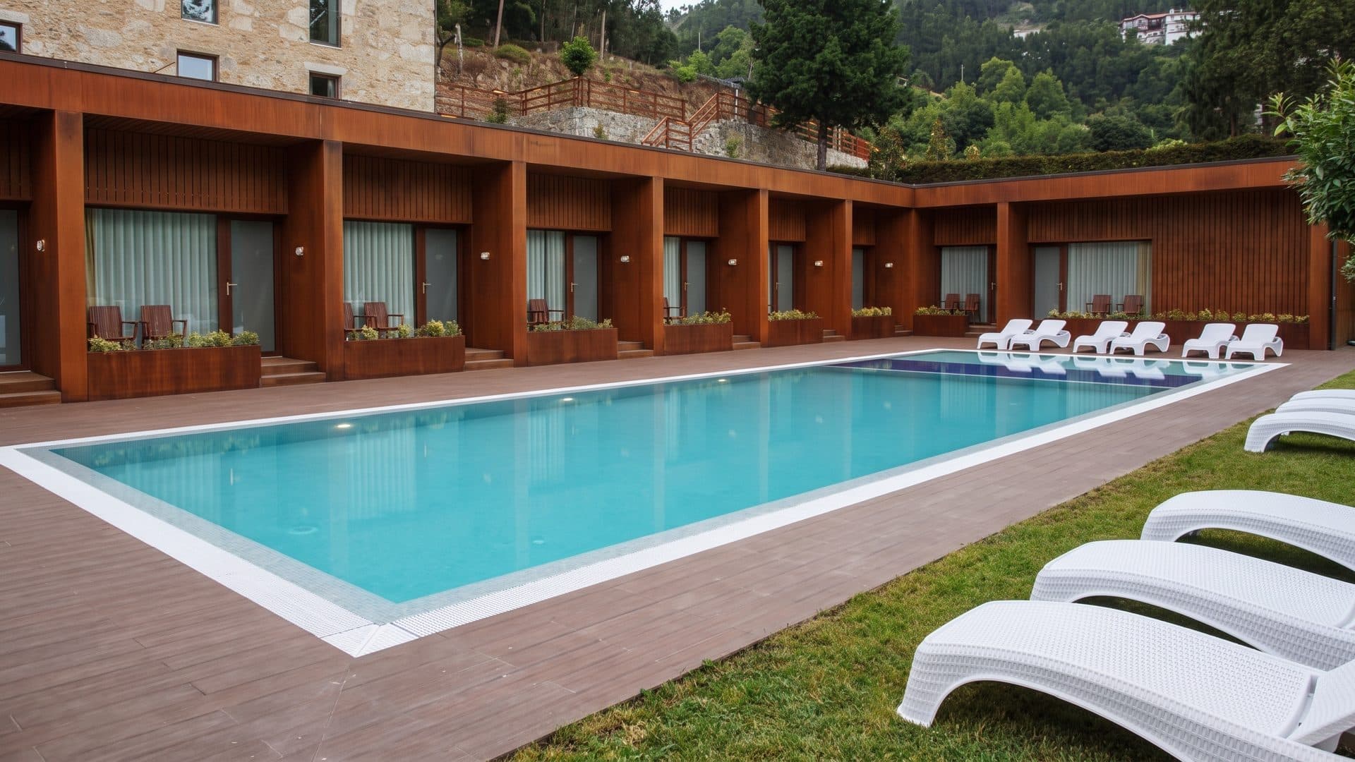 The pool of Termas da Moimenta by the spa building with loungers along the far side