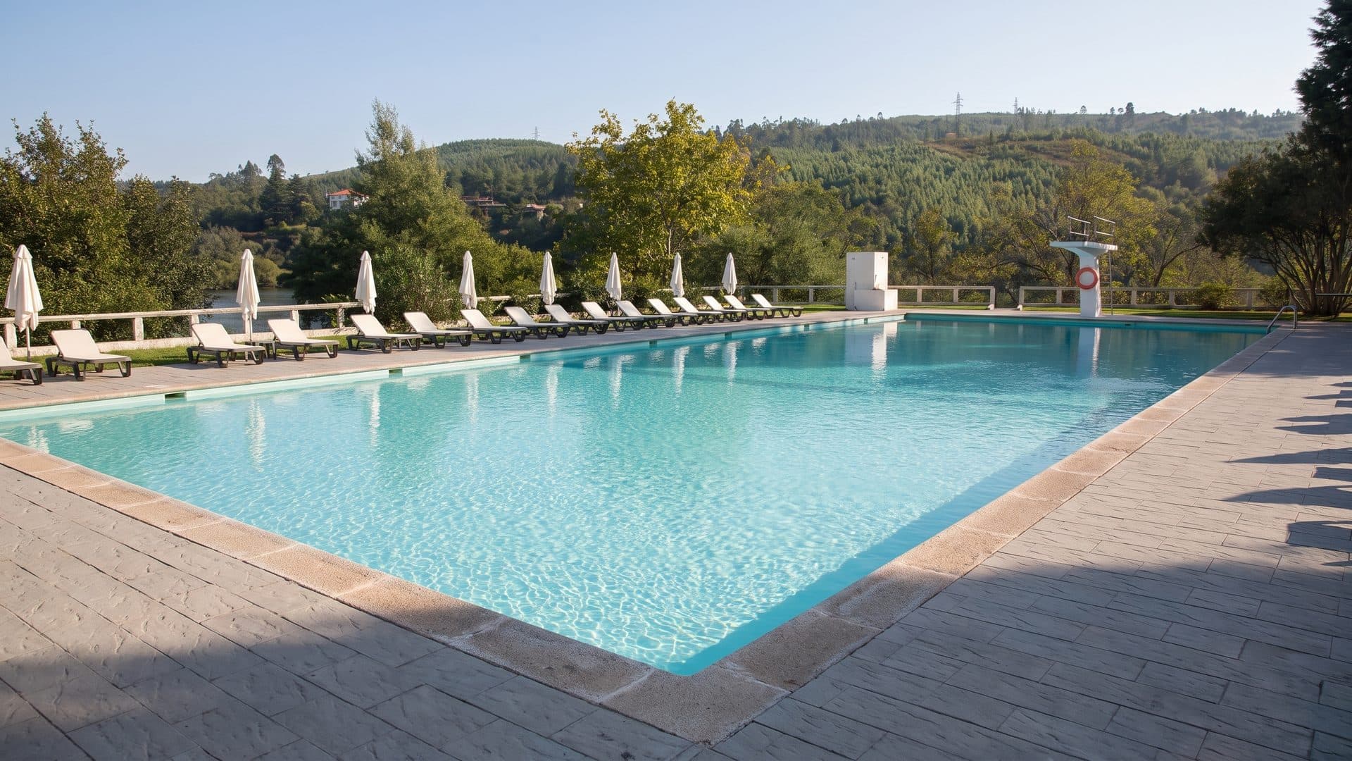 The outdoor pool of Caldas de Aregos with loungers along its side above the river