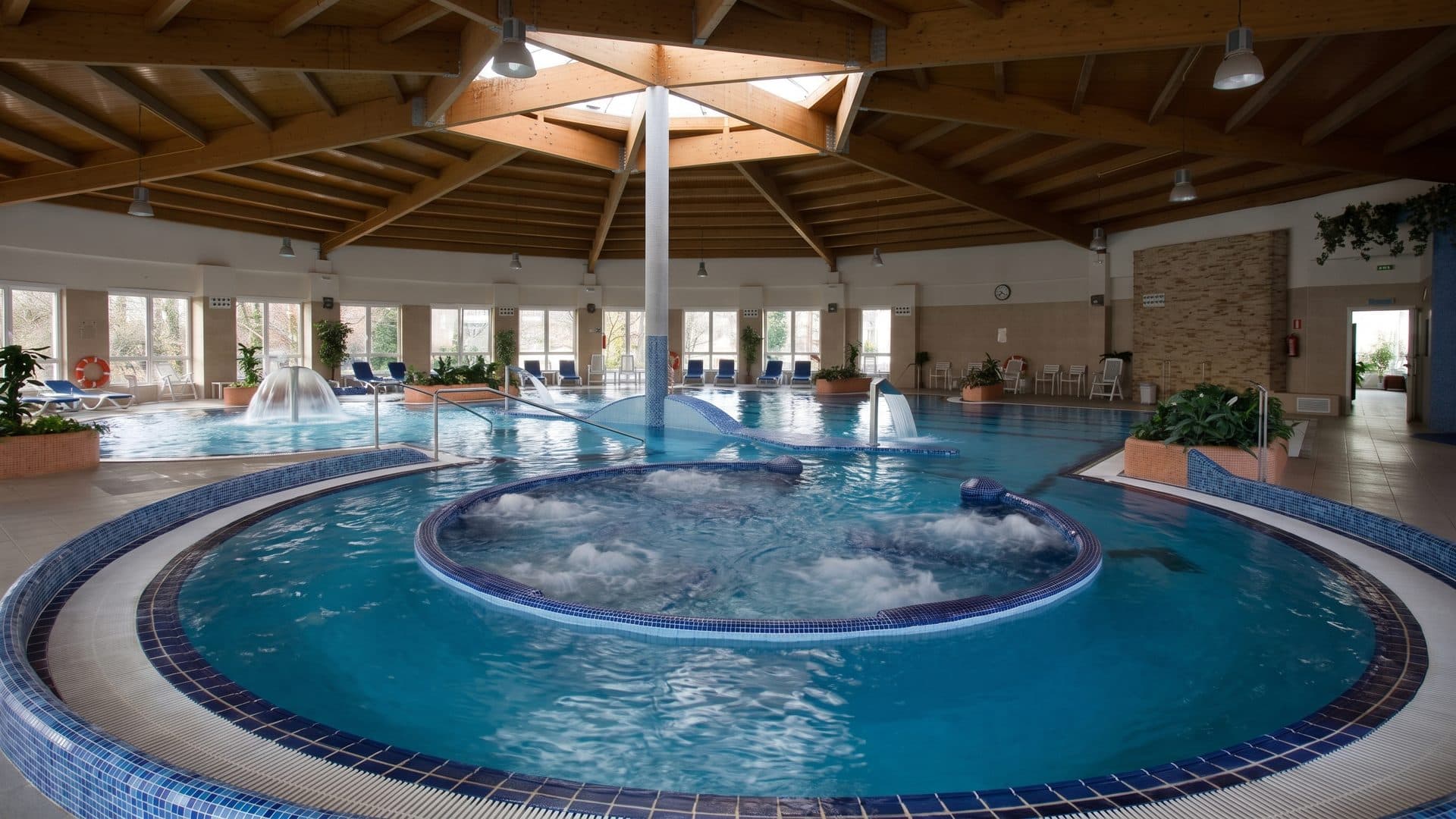 The circular indoor thermal pool at Cuntis under a timber dome, jets bubbling at its centre