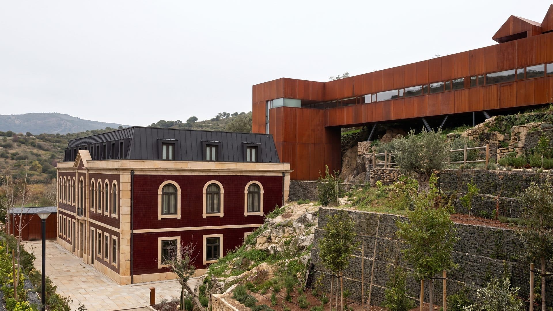 The red spa building of Termas de Longroiva on its terrace with the hills behind