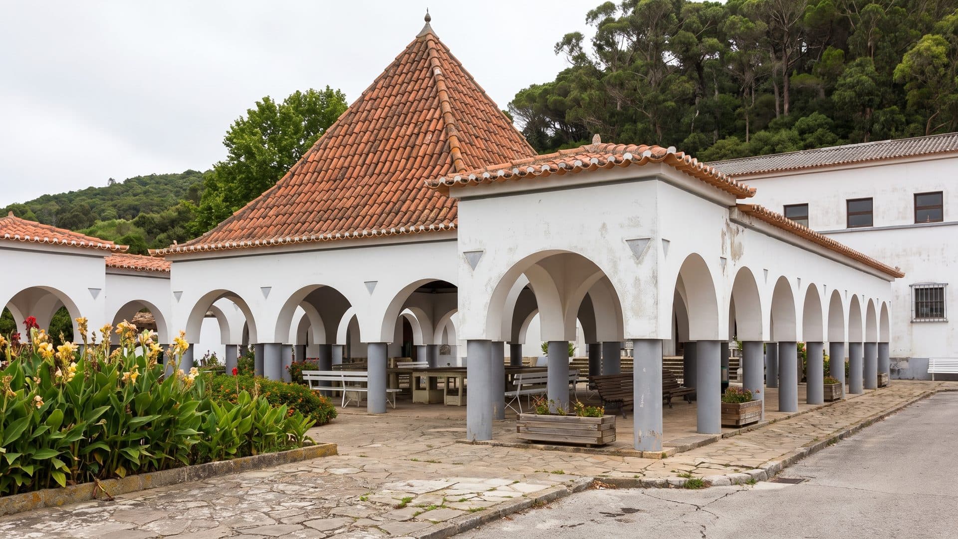The white arcaded bath pavilion at Vimeiro under its red tile roof, flowers in the garden beds in front