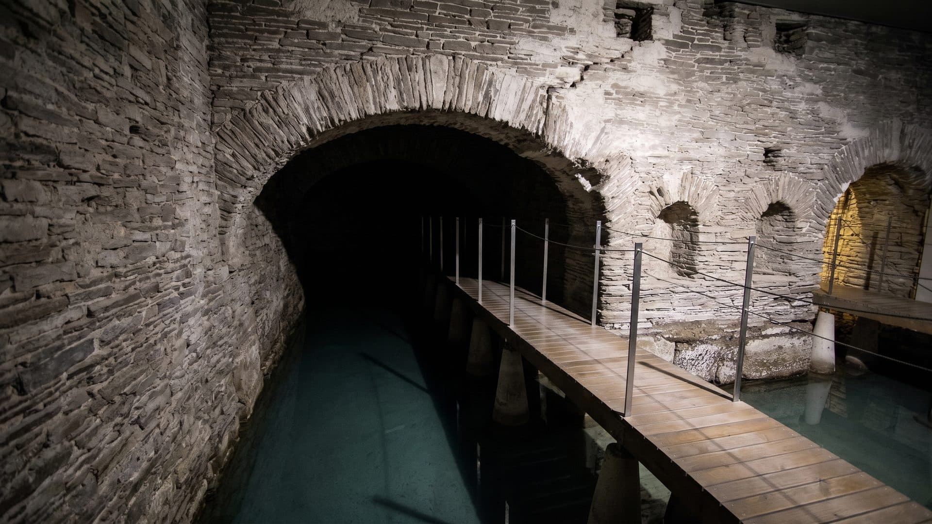 The vaulted Roman bath chamber of Lugo with the water running away beneath the arch