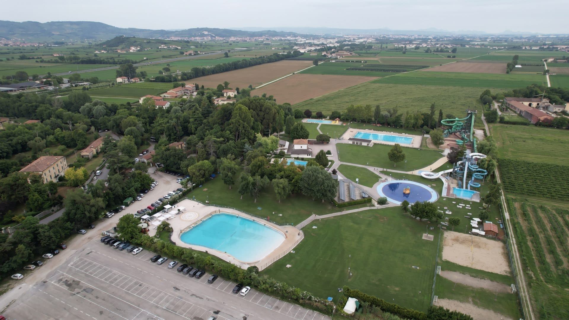 Terme di Giunone from the air: thermal pools and a water slide among lawns and trees in the Italian countryside.