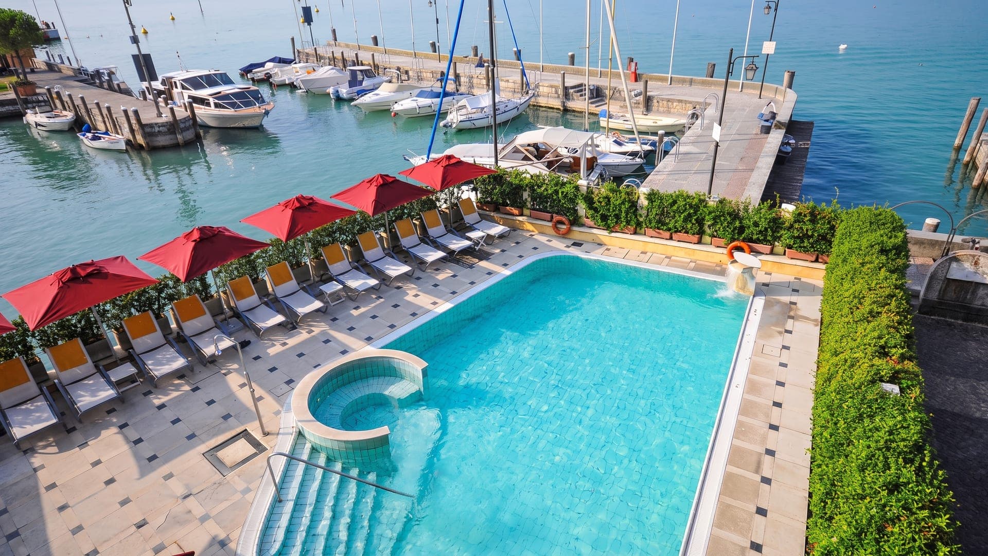 Pool with red parasols on the lakeshore beside the moorings
