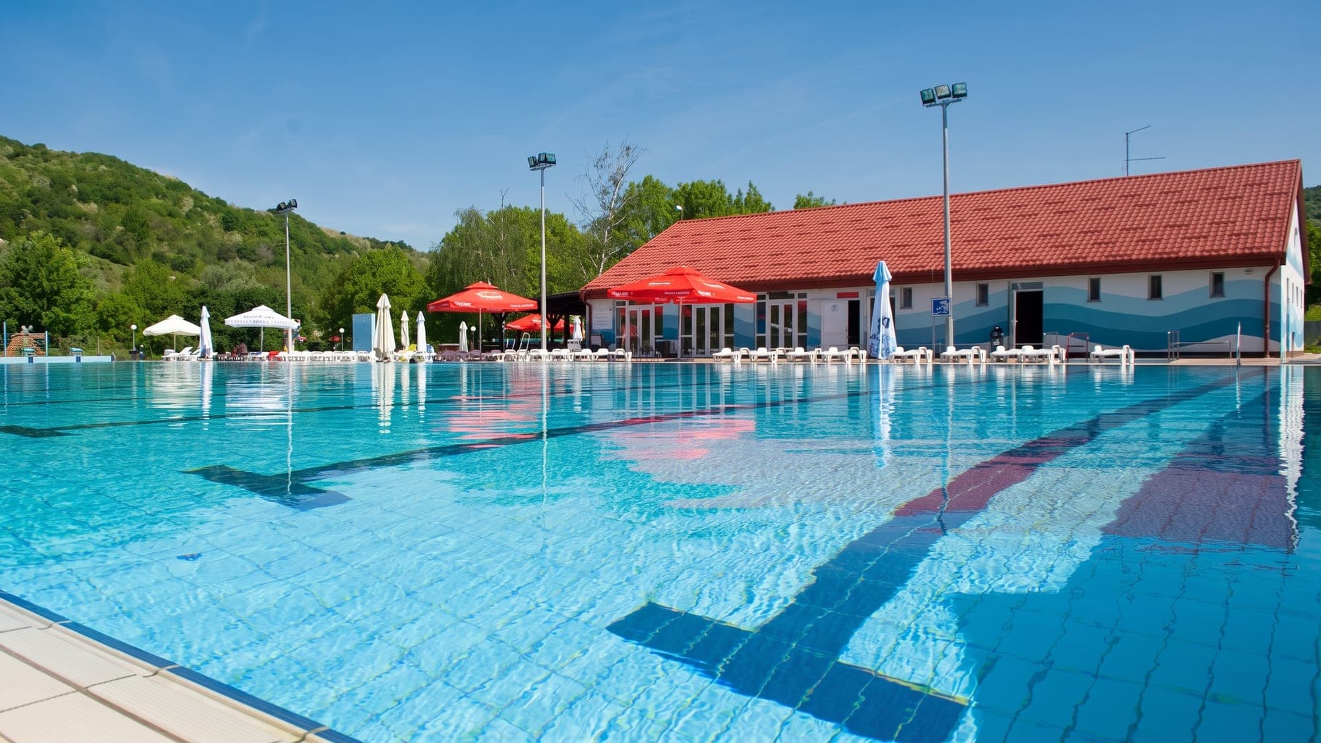 The outdoor pool at Terme Jezercica in Donja Stubica, in front of the red-roofed bath building.