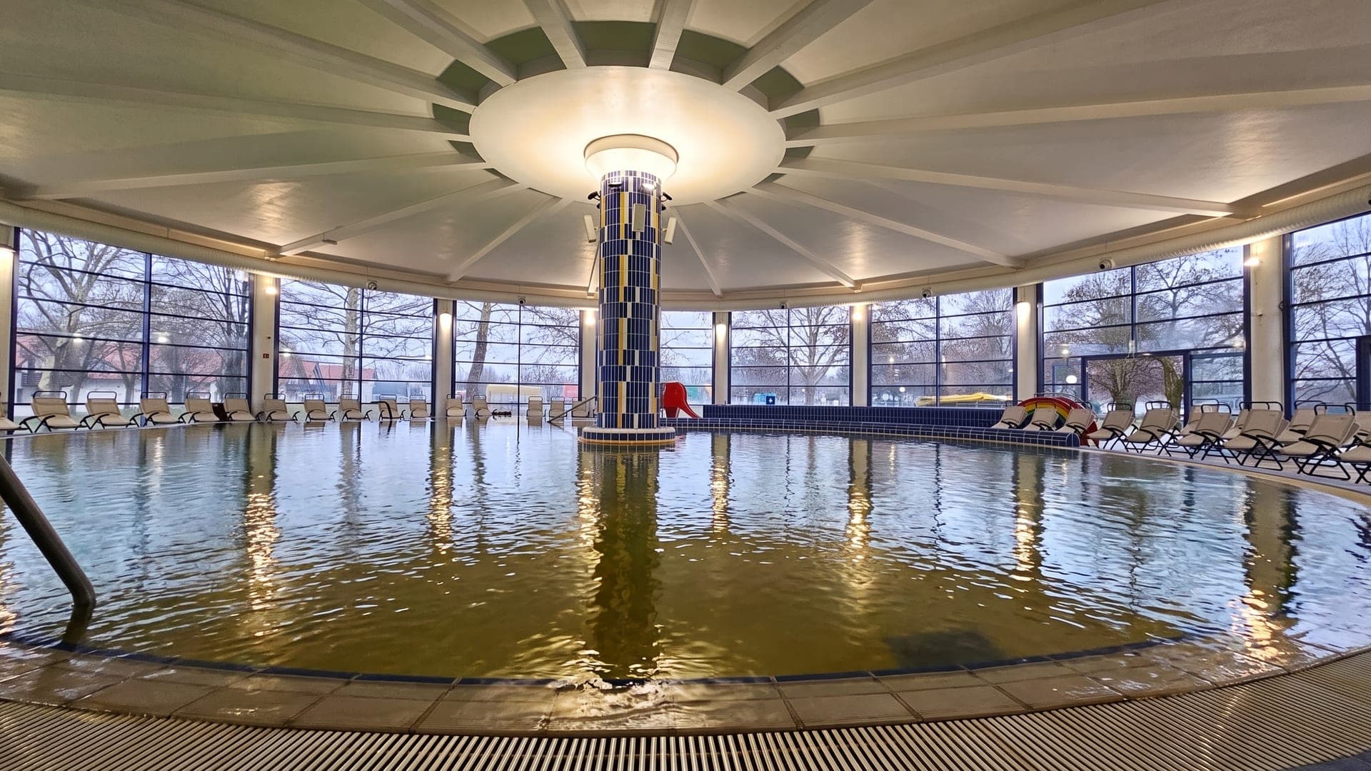 The circular indoor pool at Terme Lendava under a fluted dome, its dark mineral water around a mosaic column.
