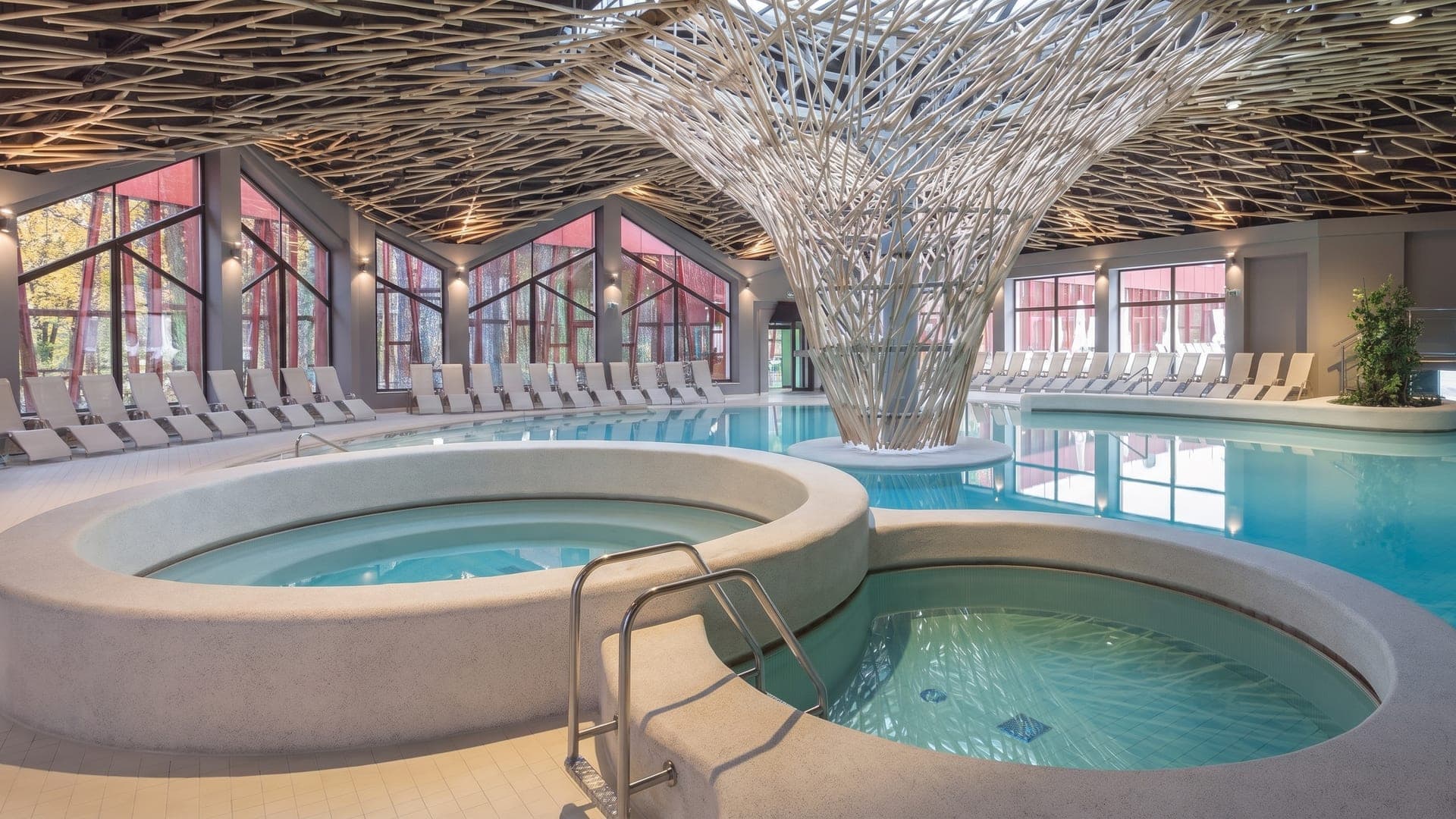 The Termalija hall at Terme Olimia, its pools around a white branching column that spreads across the ceiling.