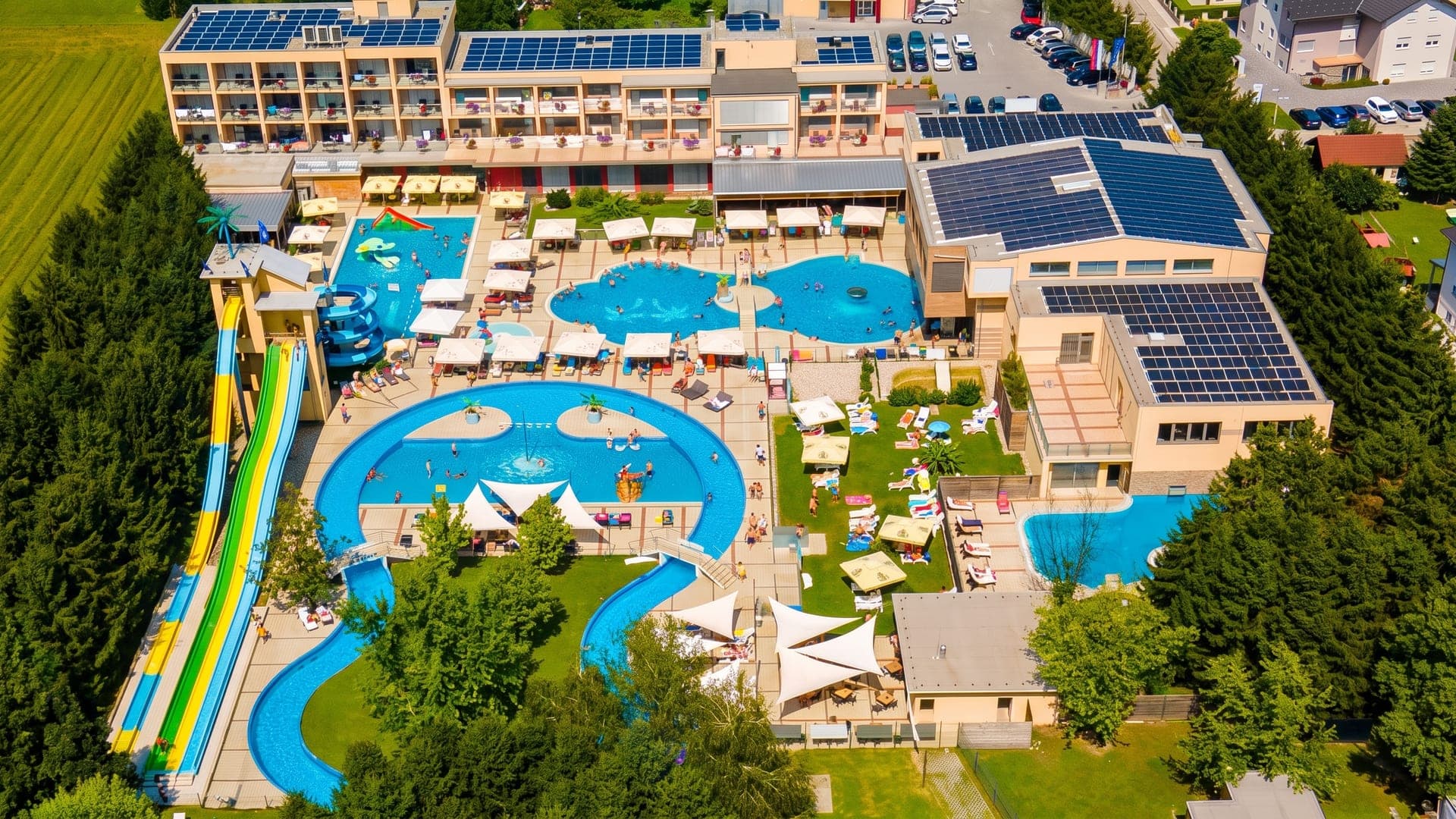 Terme Paradiso in Dobova seen from the air, its pools and coloured waterslides among lawns and trees.