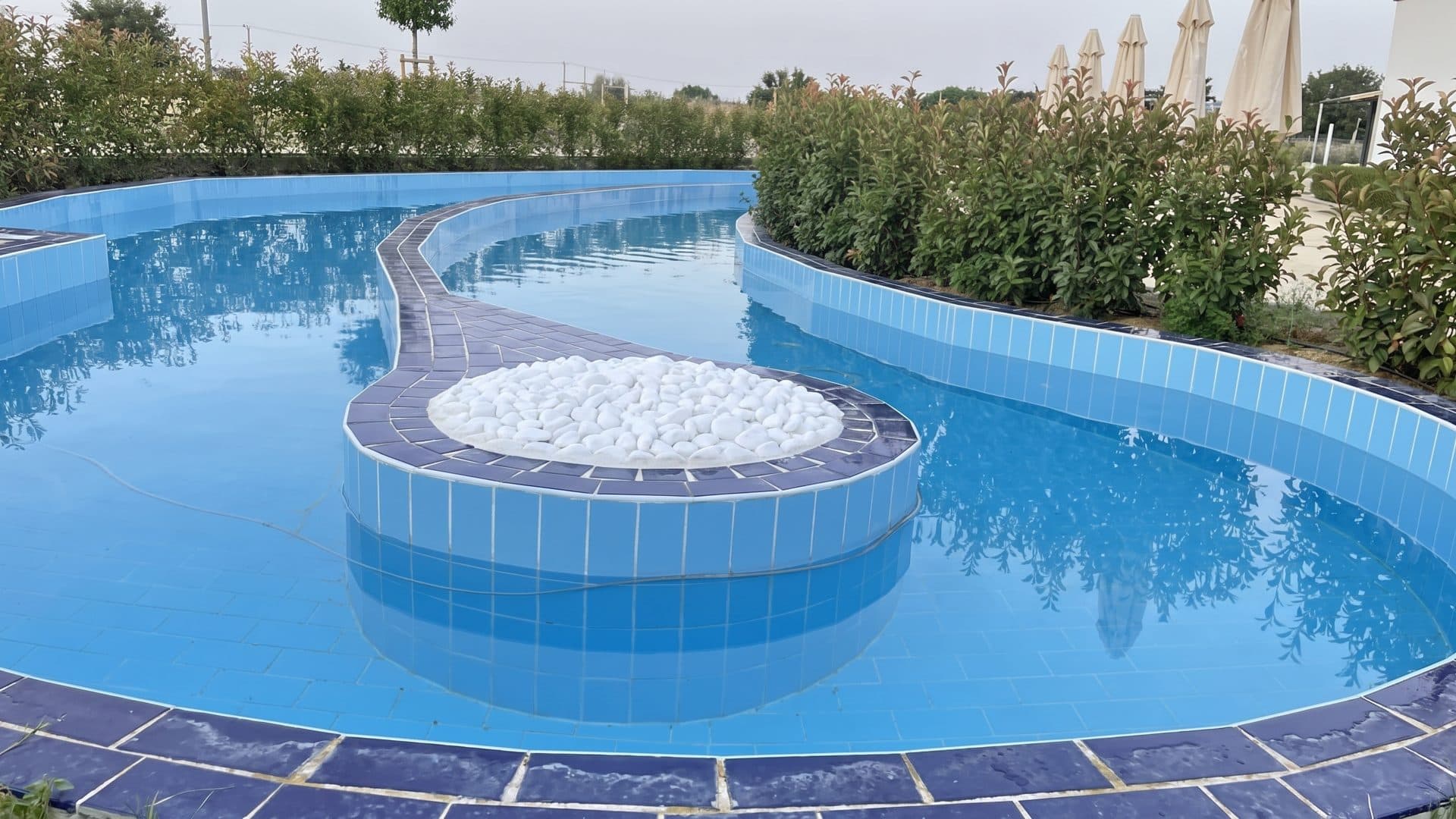 The curved outdoor pool at Pautaliya with a round bubbling basin at its centre, mosaic-tiled to the water's edge