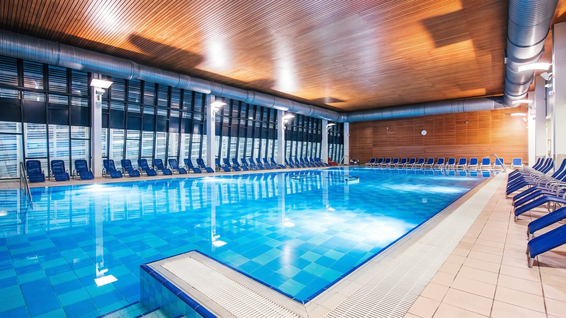 The indoor pool at Terme Vivat in Moravske Toplice, under a timber ceiling with a wall of windows onto the park.
