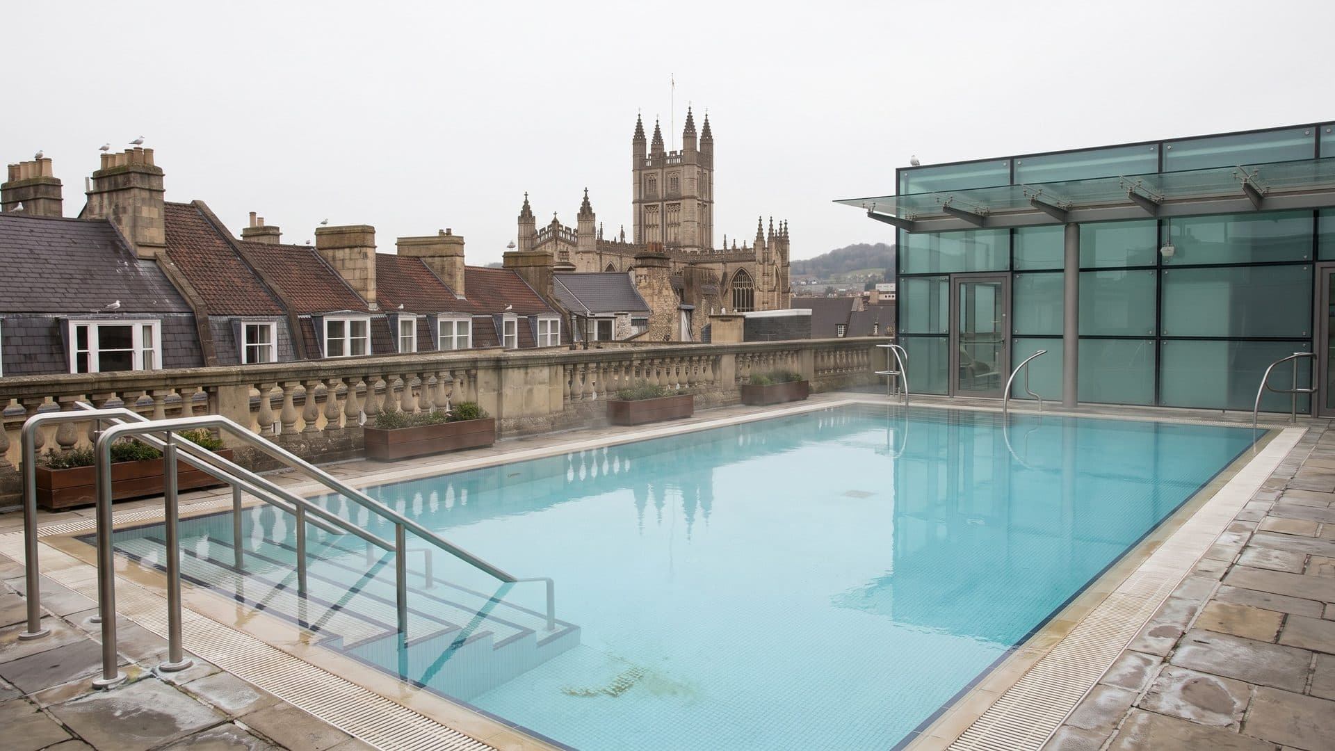 The rooftop pool of Thermae Bath Spa with the towers of Bath Abbey and the stone rooftops beyond