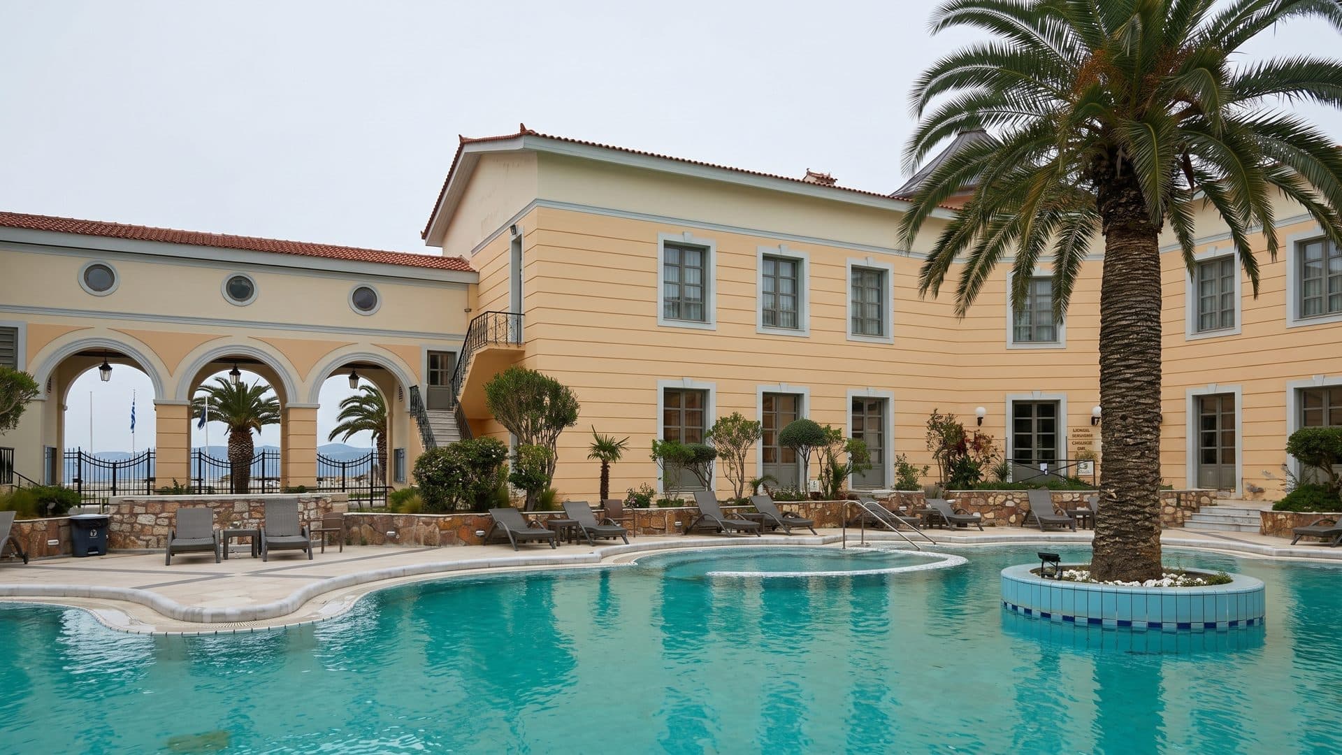 The outdoor thermal pool at Thermae Sylla in Edipsos below the yellow neoclassical bath building and its arcade