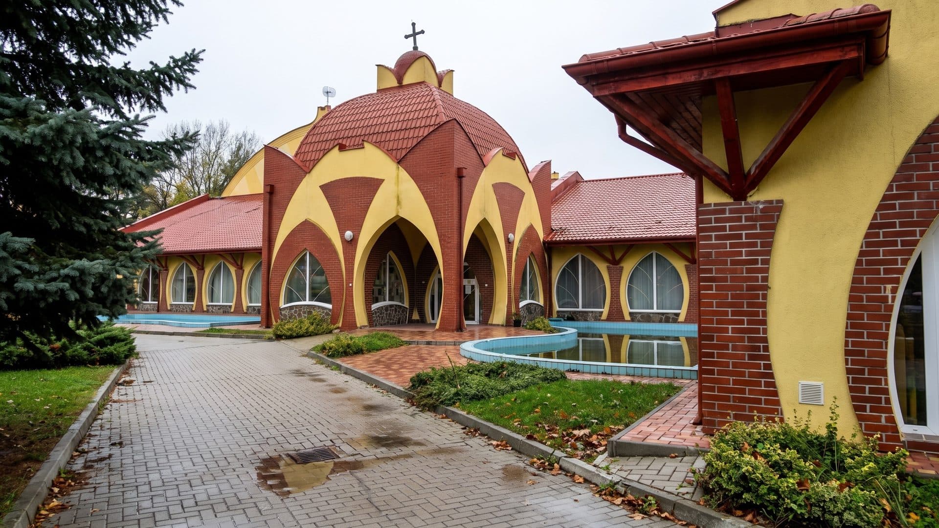 The fairy-tale bath building with red and yellow domes and arched windows, seen from a brick path