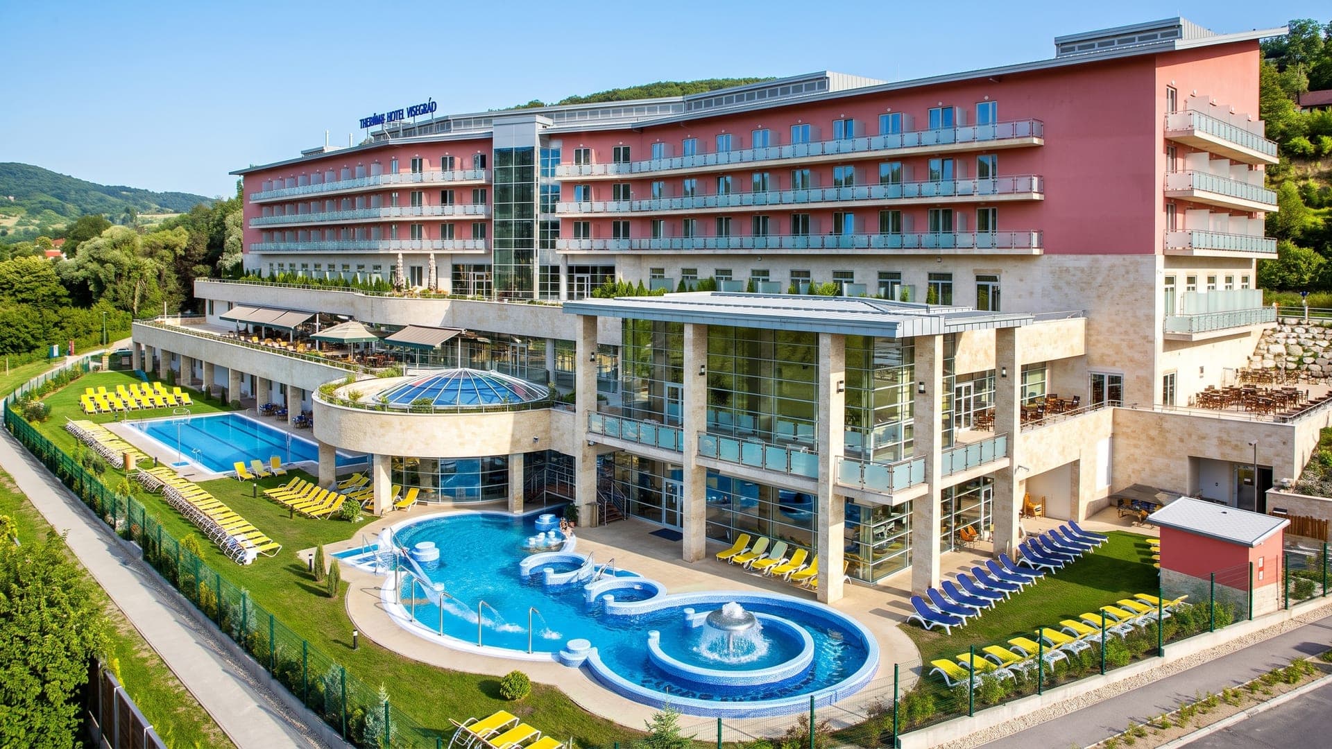 The Thermal Hotel Visegrad above its terraced outdoor pools, with the wooded hills of the Danube Bend behind.