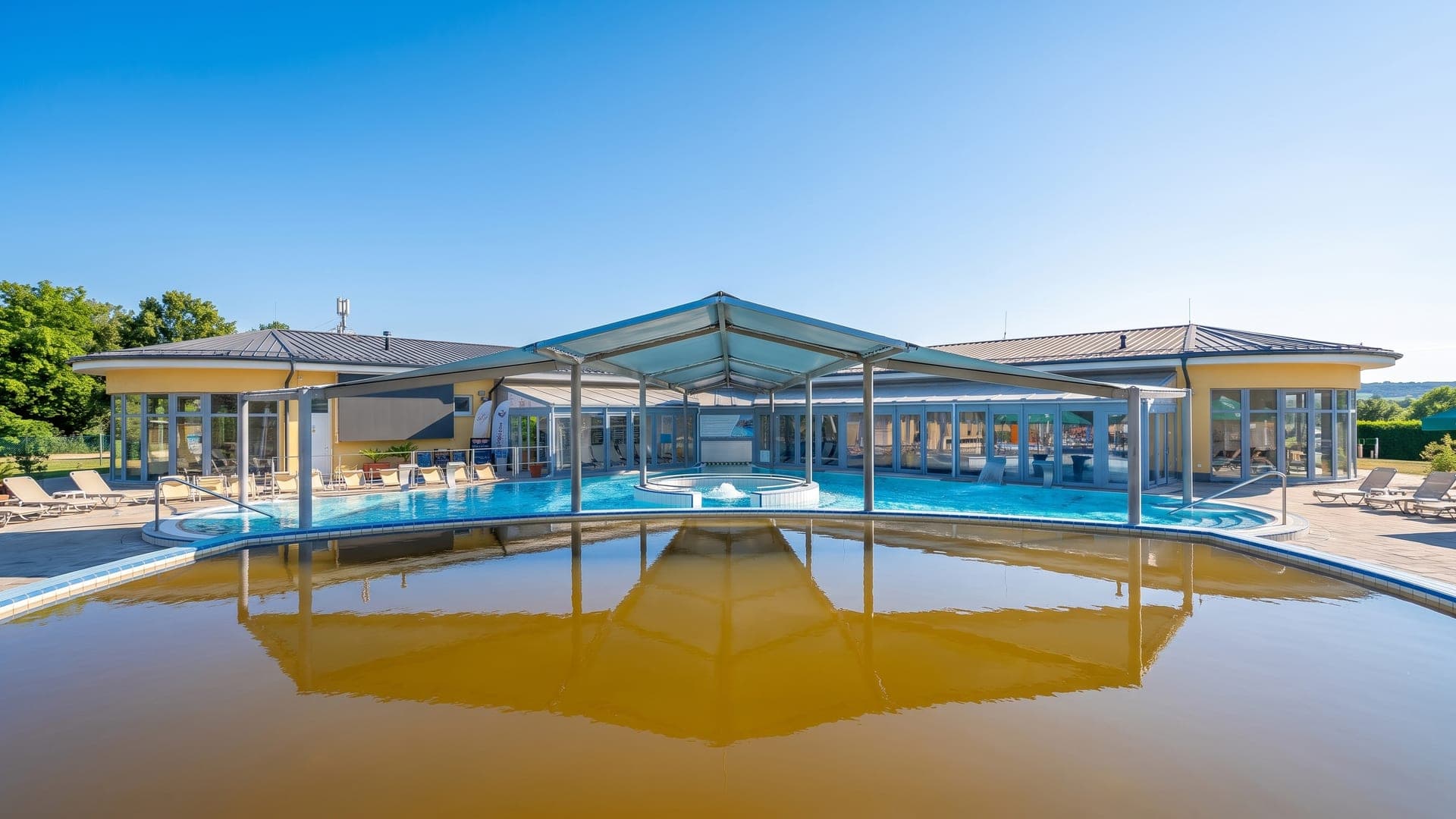 Pools under a tensile canopy, a brown mineral basin in the foreground