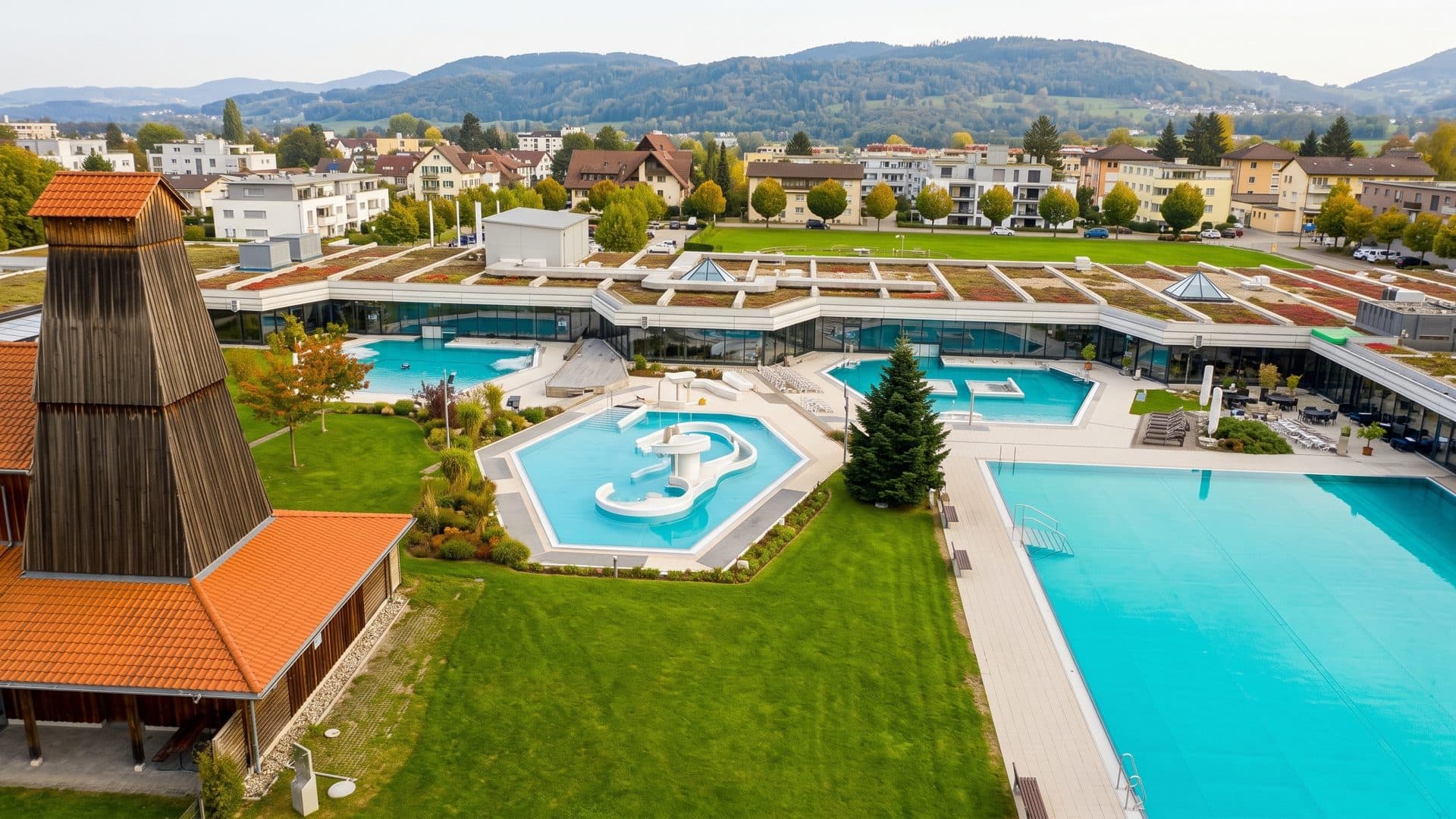 The thermal baths from above: the long low building with its green roofs and the outdoor pools on the lawn.
