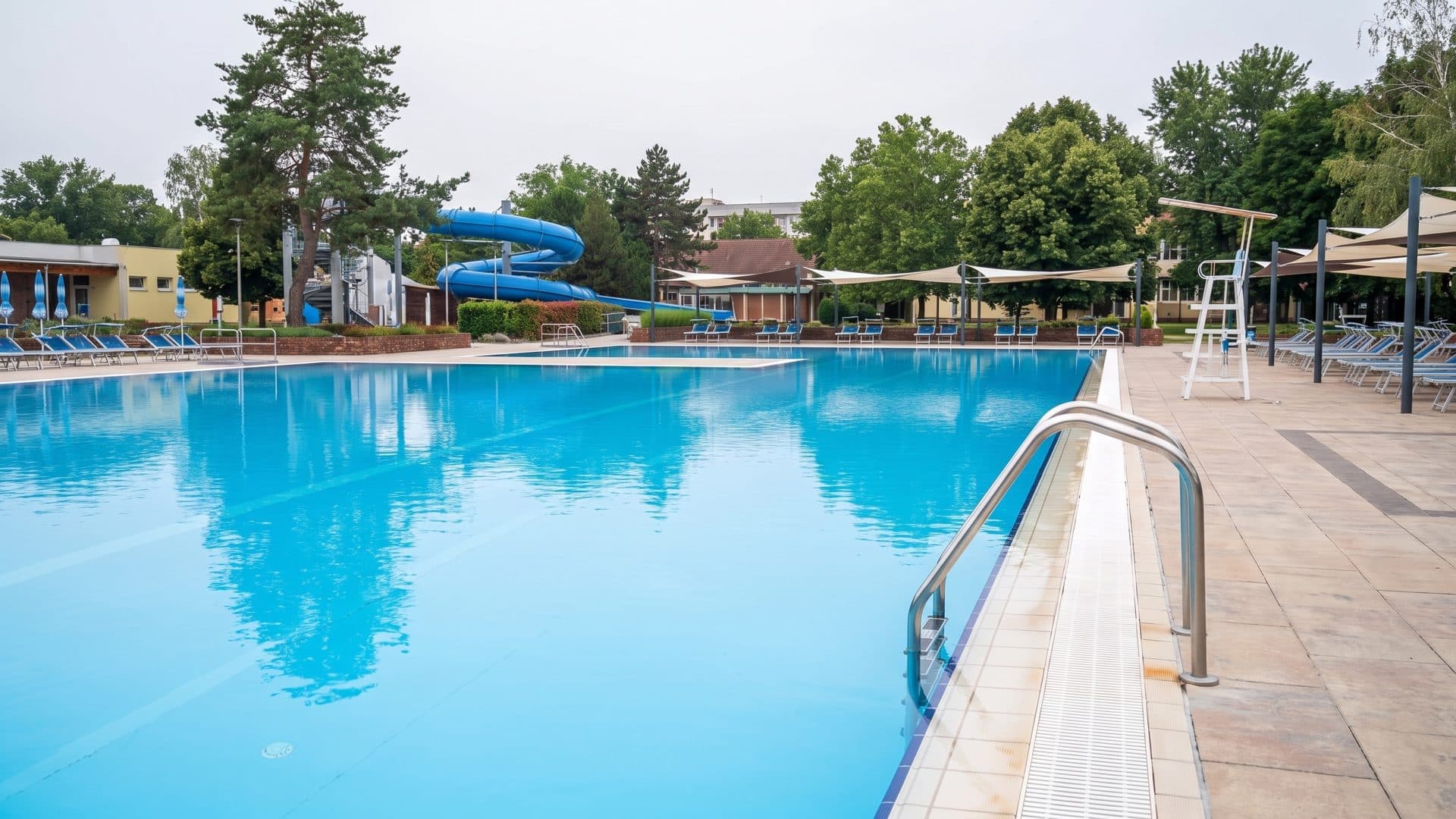The large outdoor pool at Thermalpark DS in full blue water, a slide and loungers along the far side