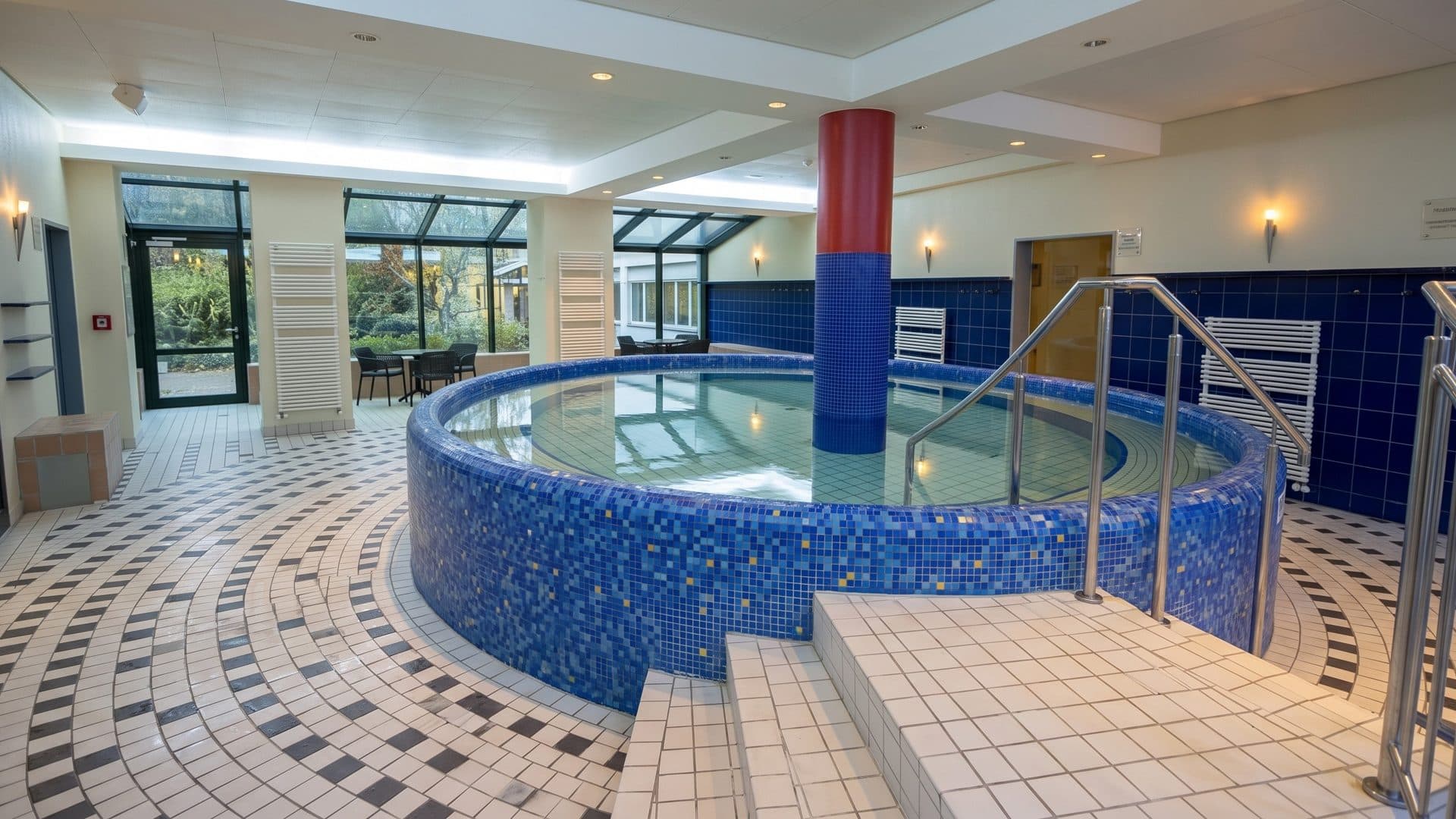 The round blue-tiled brine pool of the Thermalsolbad Salzgitter-Bad around a red column, on a patterned tile floor