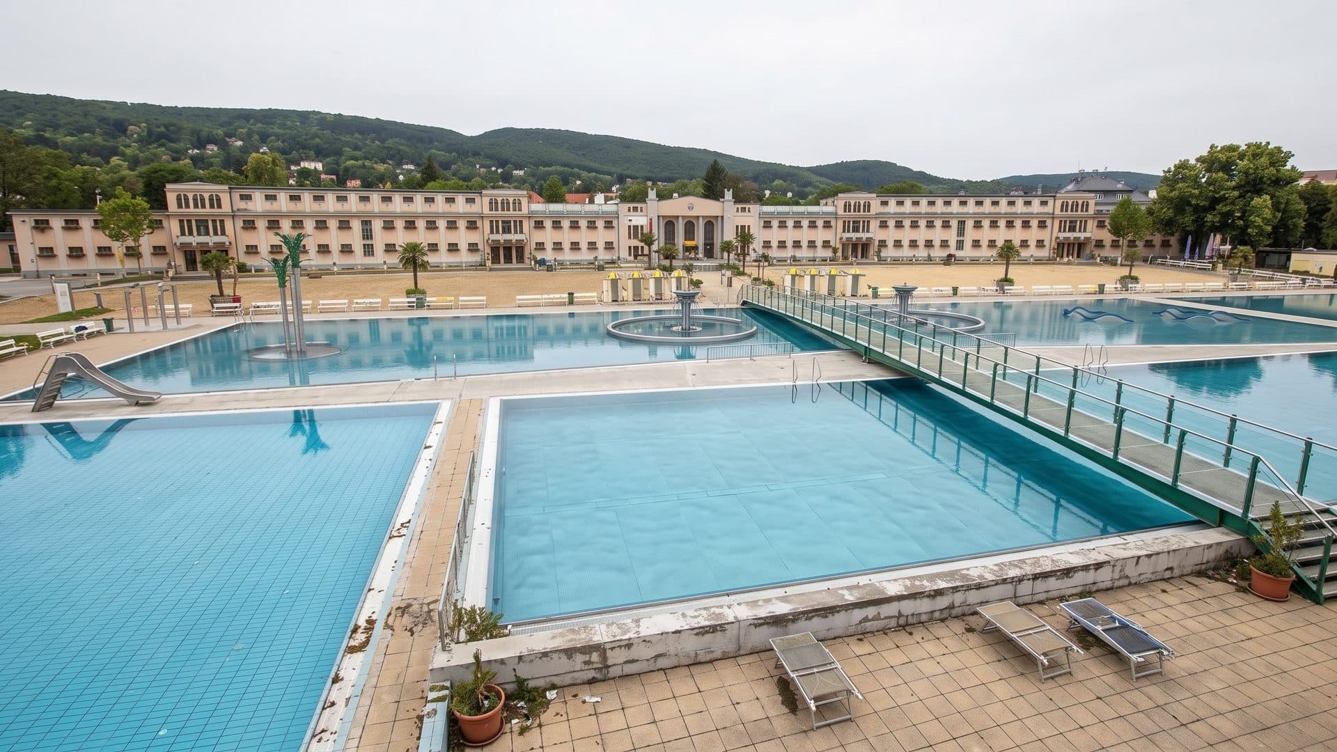 The pools of the Thermalstrandbad Baden with a glass-railed walkway, the long historic bath building behind