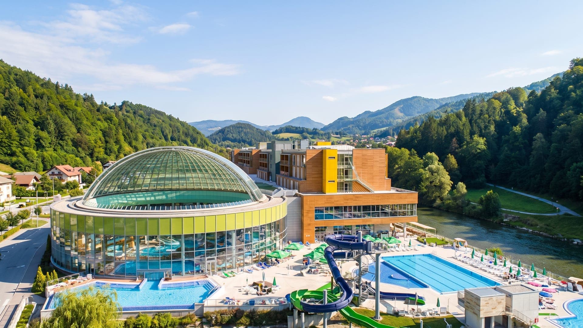 Thermana Lasko seen from the air, its glass-domed thermal centre beside the river Savinja with wooded hills around.