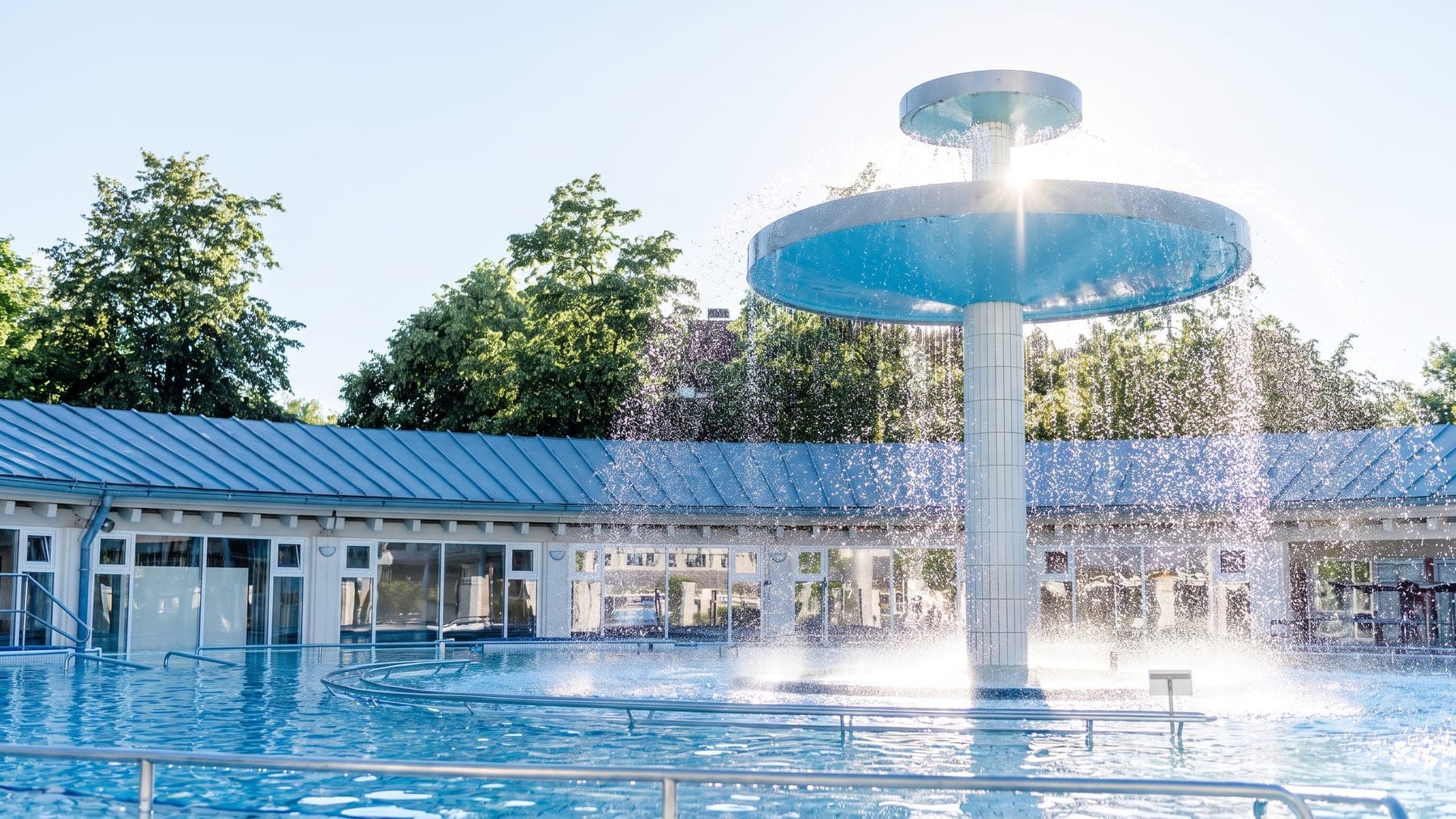 The outdoor pool at Therme Eins in Bad Fuessing, with a two-tier mushroom fountain pouring into the water.