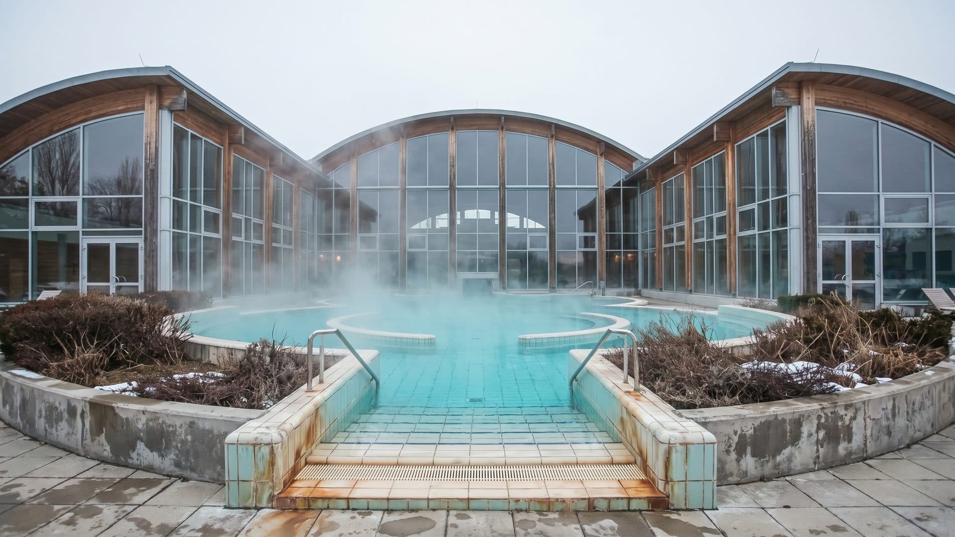 The outdoor thermal pool at Laa an der Thaya steaming in winter in front of the arched glass hall