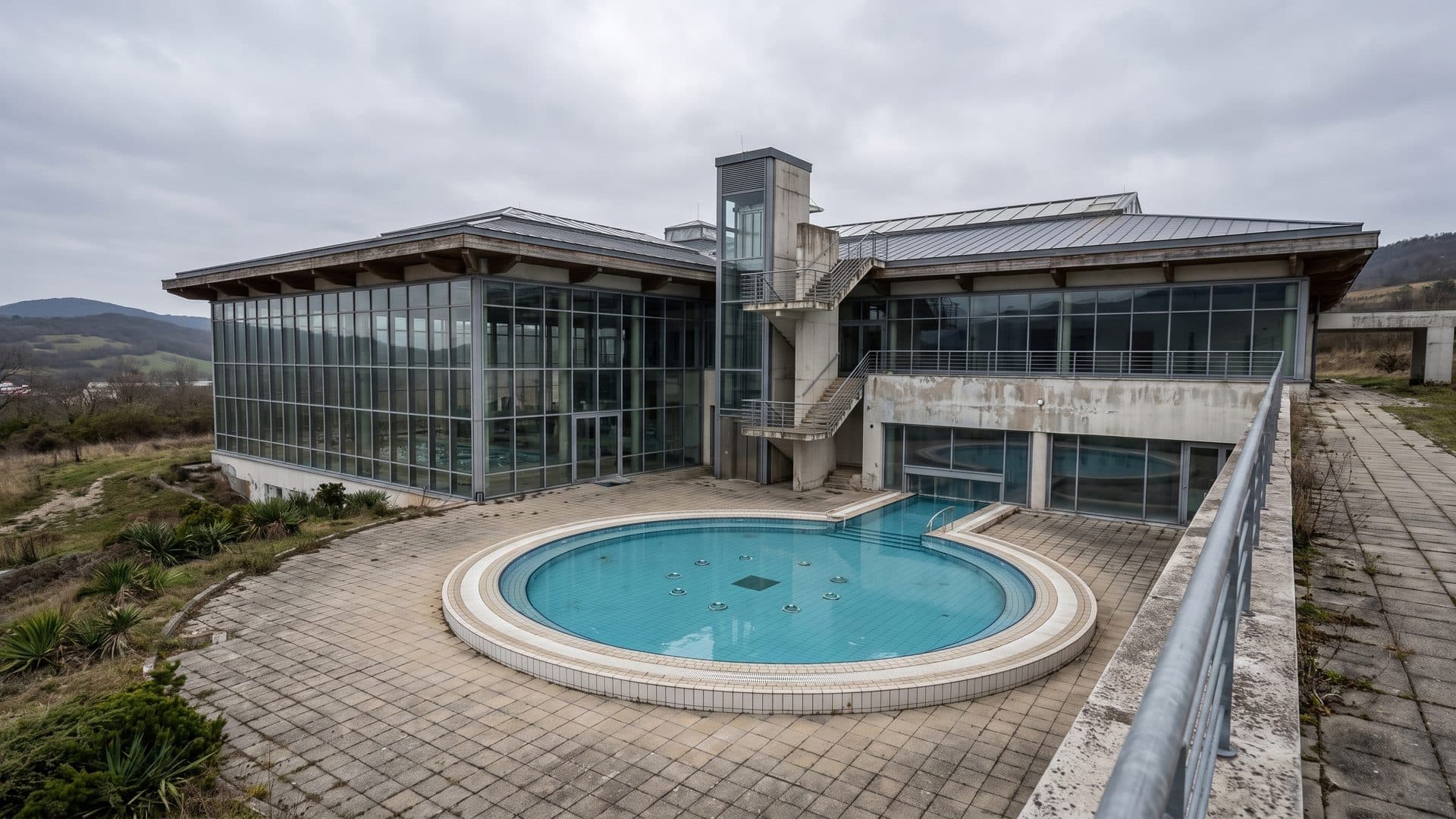 The circular outdoor thermal pool at Therme Nova Koflach, with the glazed bath hall rising behind it.
