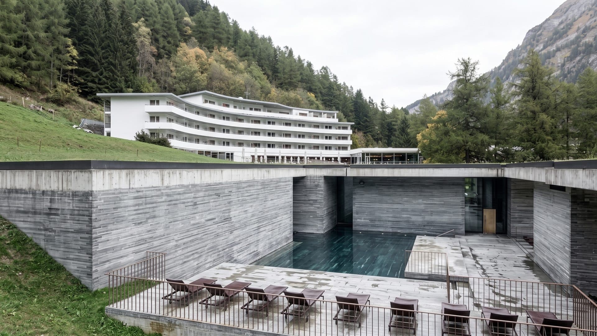 The stone baths of Therme Vals set into the hillside with an outdoor pool and the hotel behind