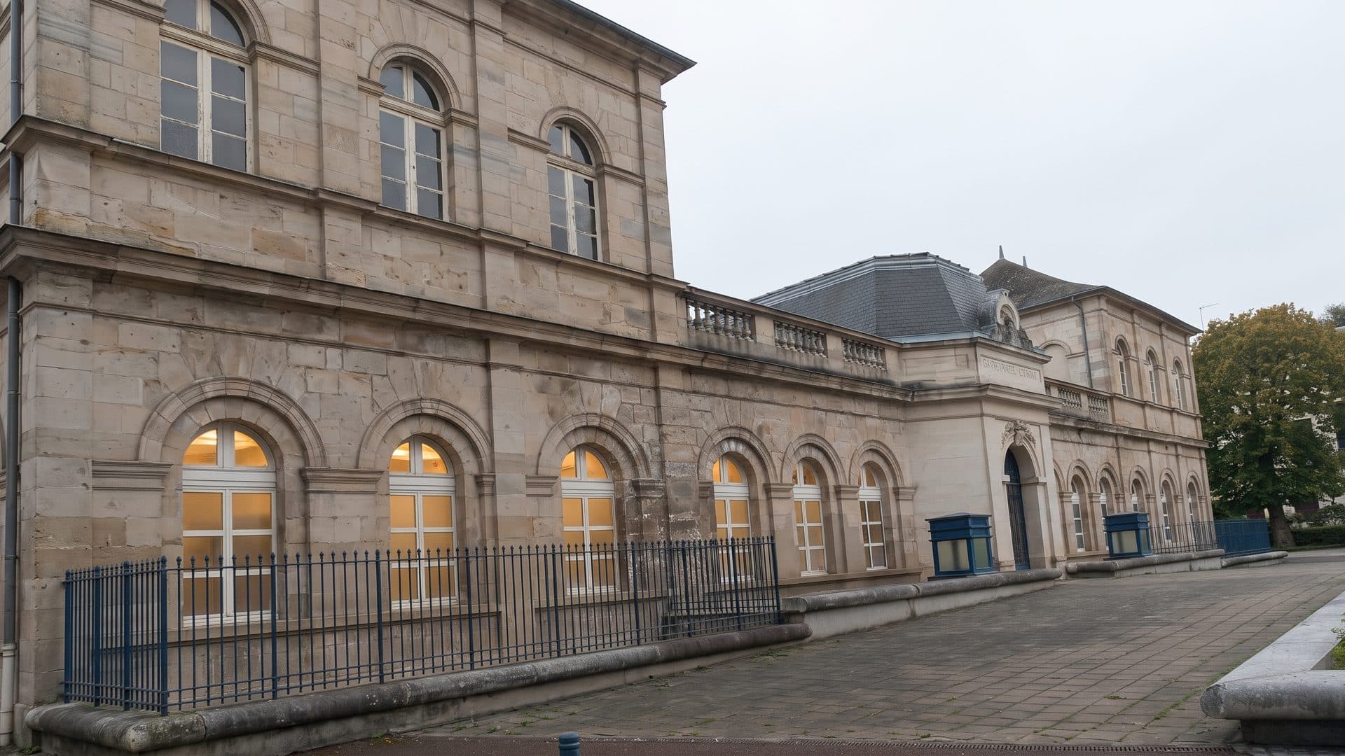 The stone neoclassical bath house of Neris-les-Bains seen along its arcaded front, tall arched windows lit from within