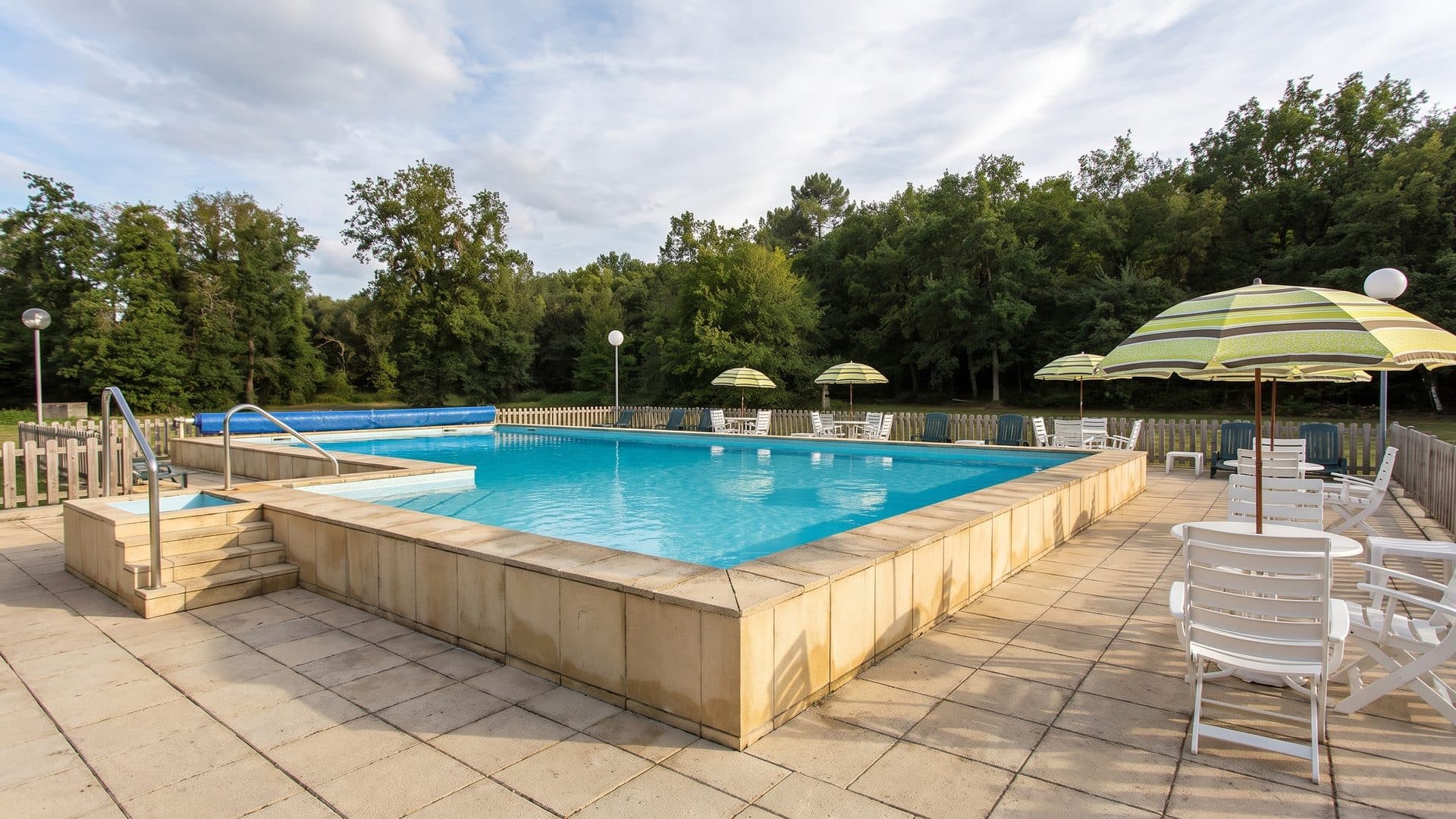 The outdoor pool of the Saubusse thermal baths with parasols and tables along the terrace