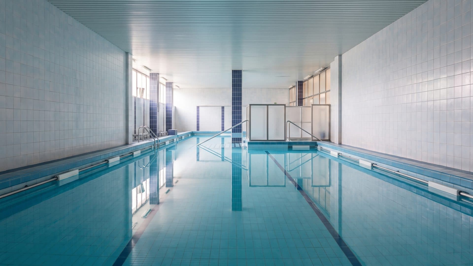 The pool of the Arenes baths seen down its length between pale tiled walls