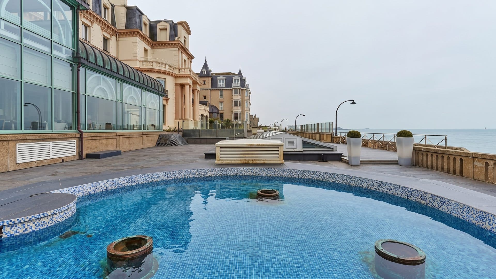 A round outdoor pool on the seafront terrace of the Thermes du Grand Hotel, the belle-epoque facade alongside