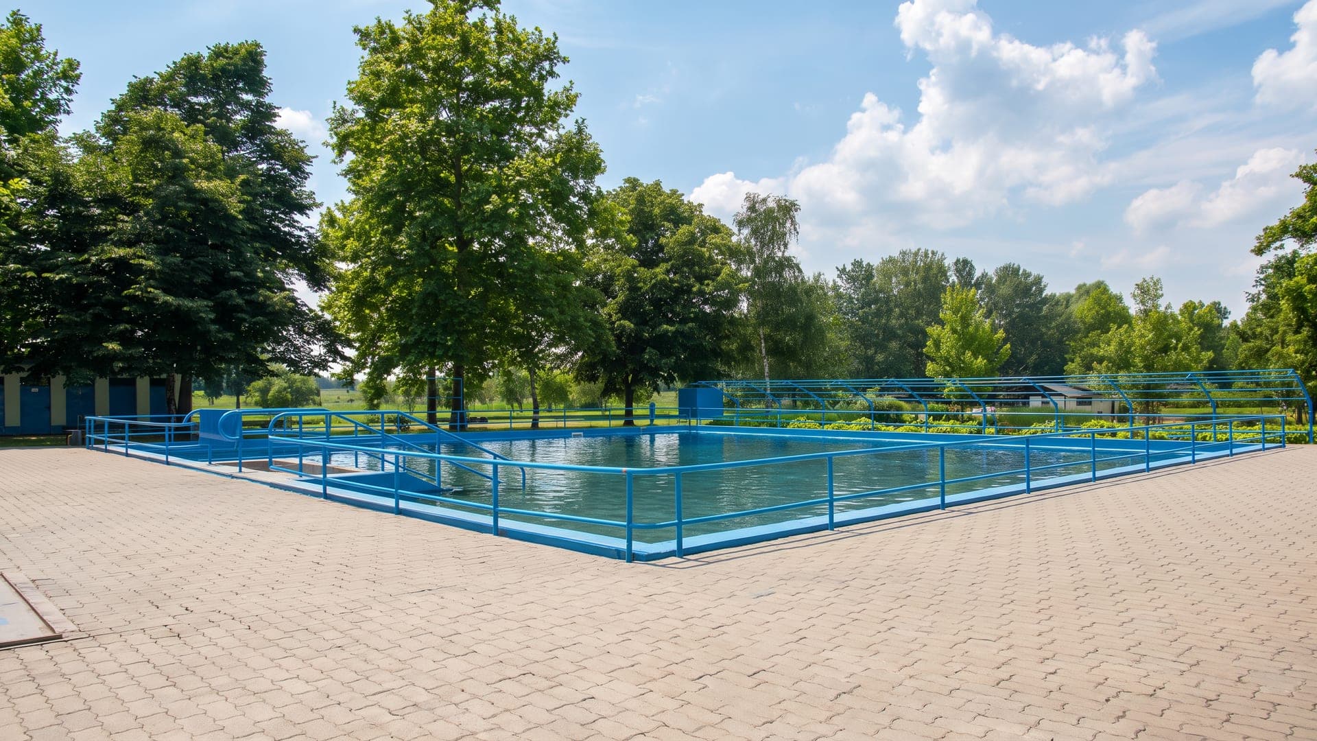 Outdoor pool with blue railings among trees