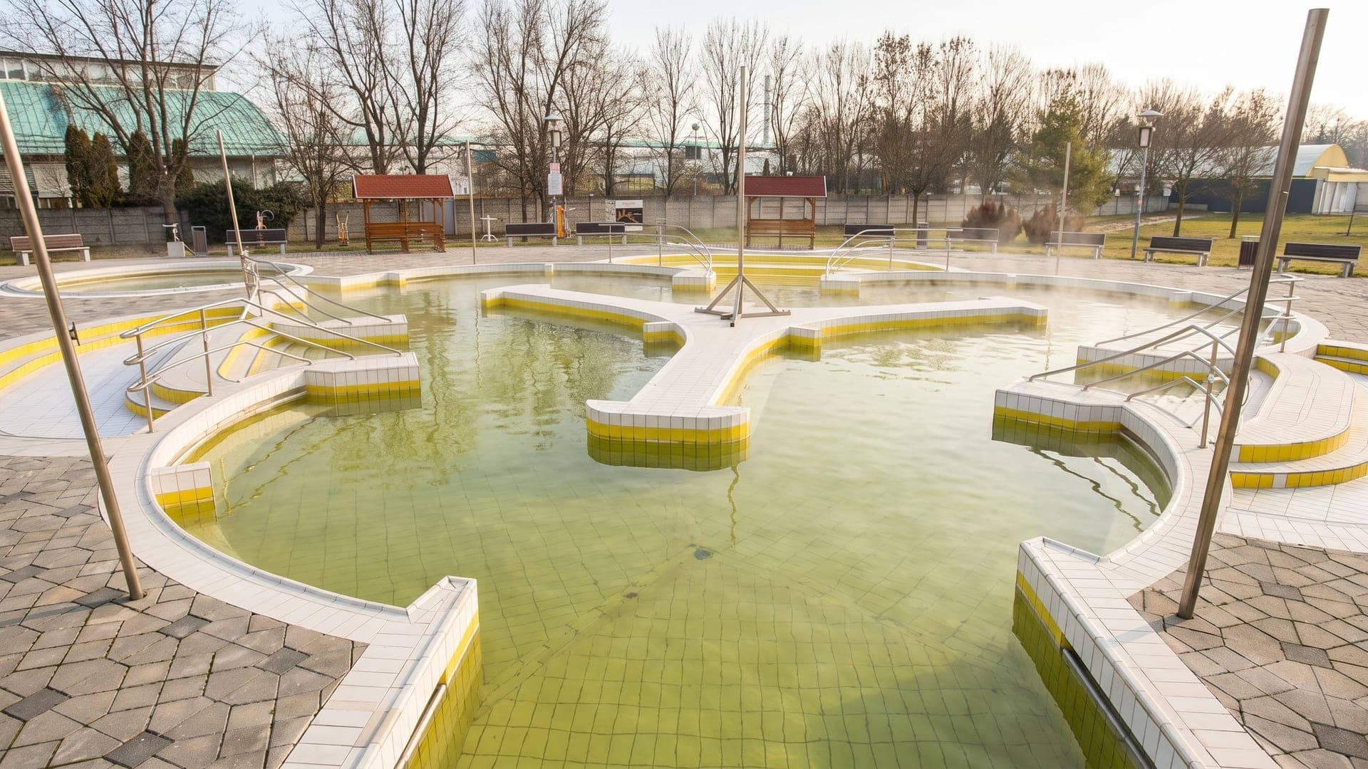 The outdoor pools at Tiszaujvarosi Gyogy- es Strandfurdo in winter, steam rising from the yellow-brown thermal water.