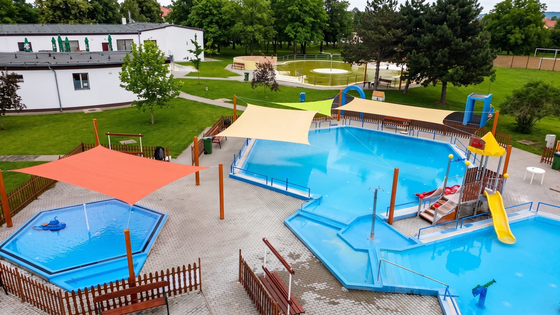 Children's pools under coloured shade sails beside the lawns