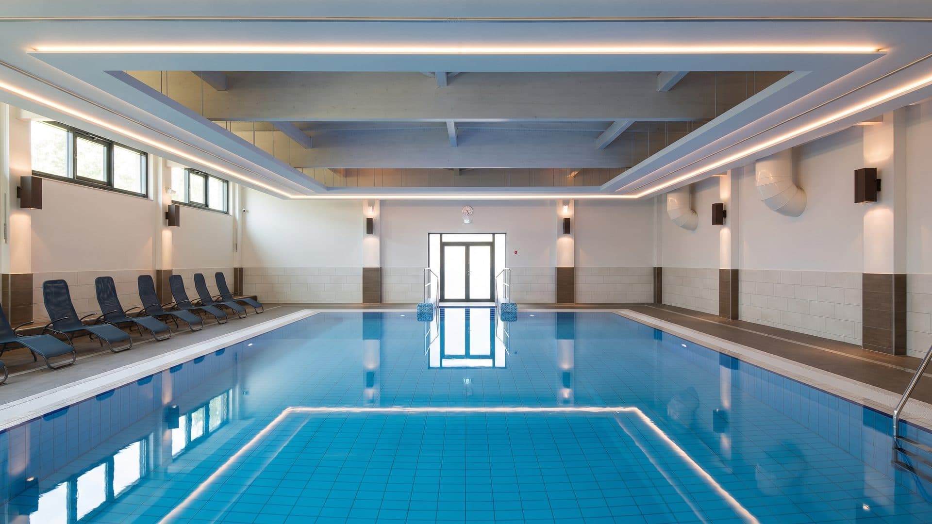 The pool of the Trixi-Bad hall seen down its length under the lit ceiling
