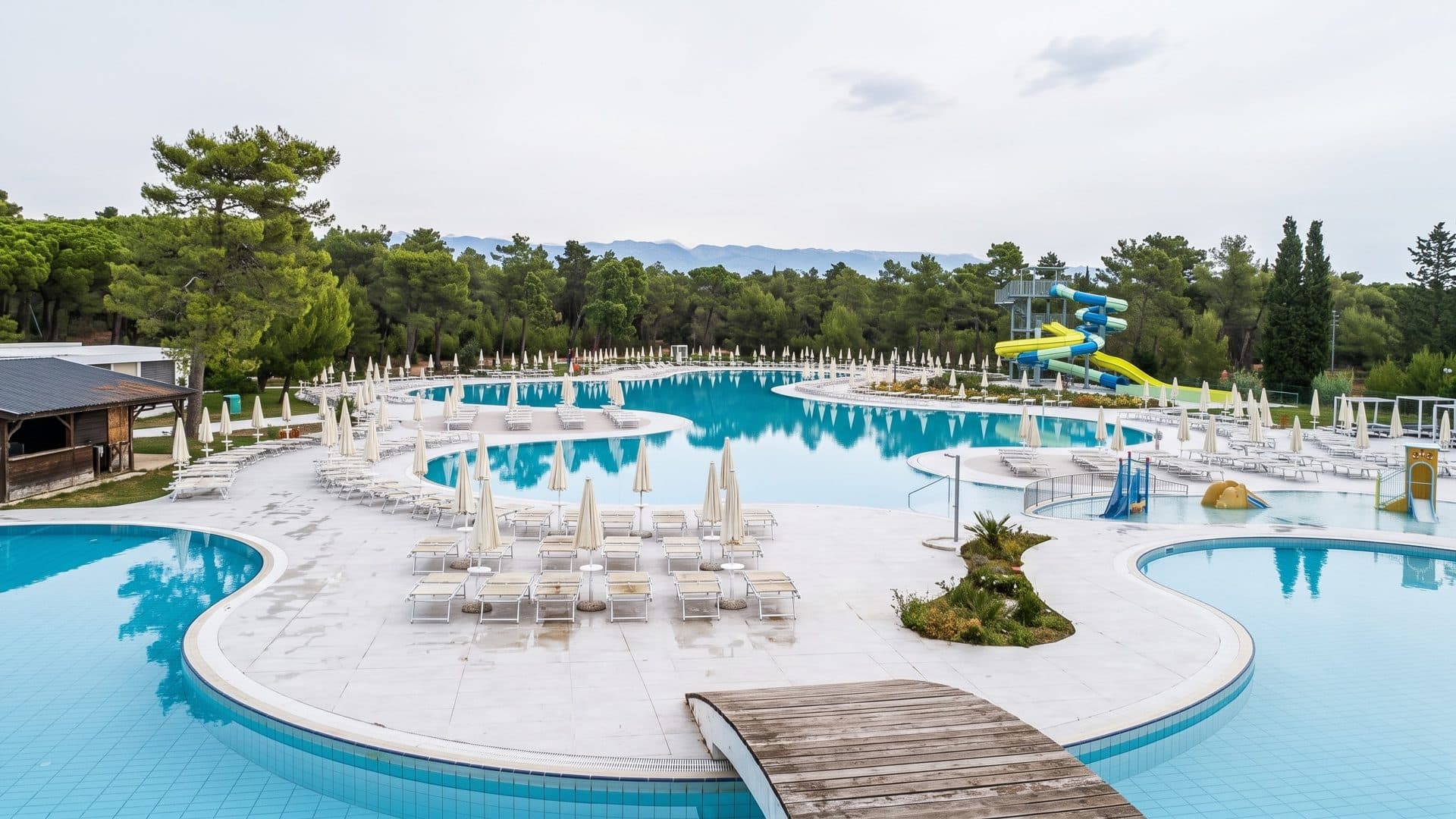 Curving outdoor pools of the Zaton Holiday Resort near Nin with white loungers and pine trees
