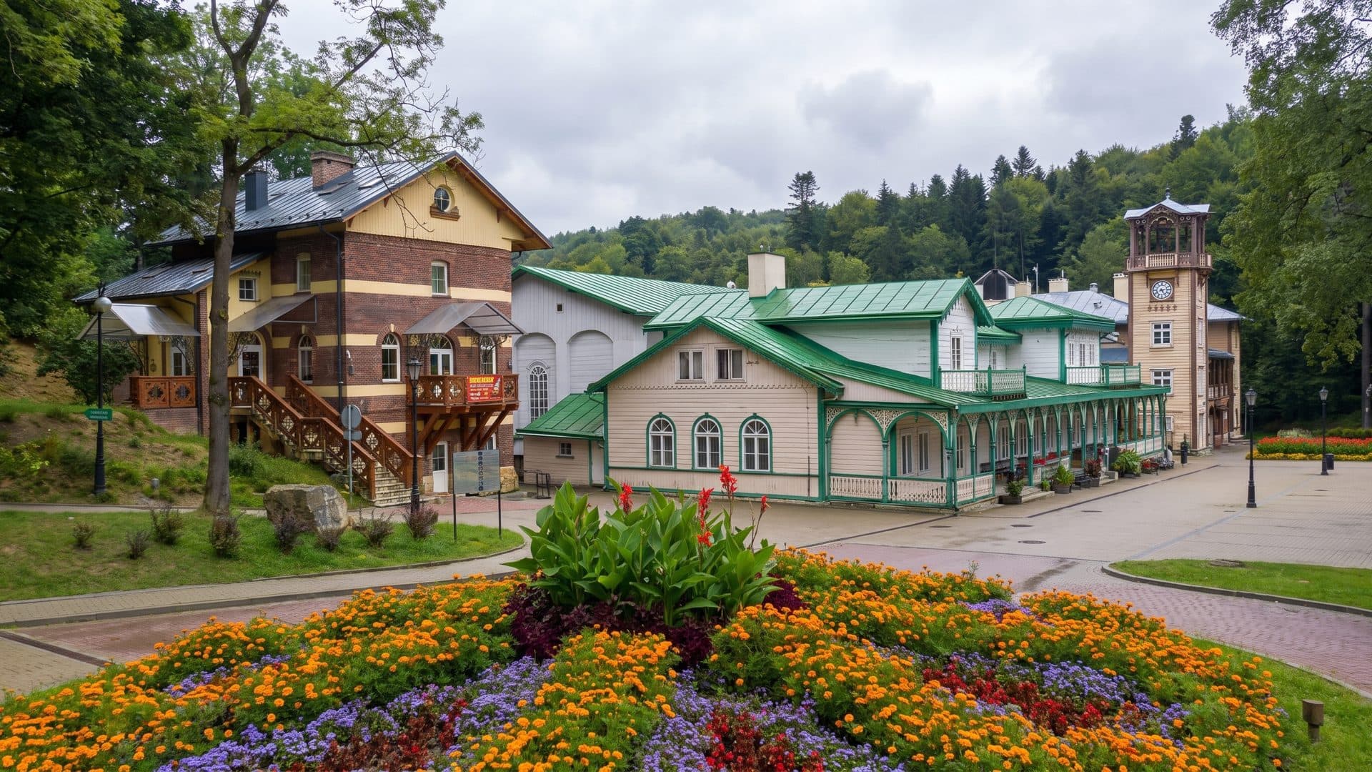 The historic timber spa pavilions of Iwonicz-Zdroj around the formal flower bed, wooded hills behind.