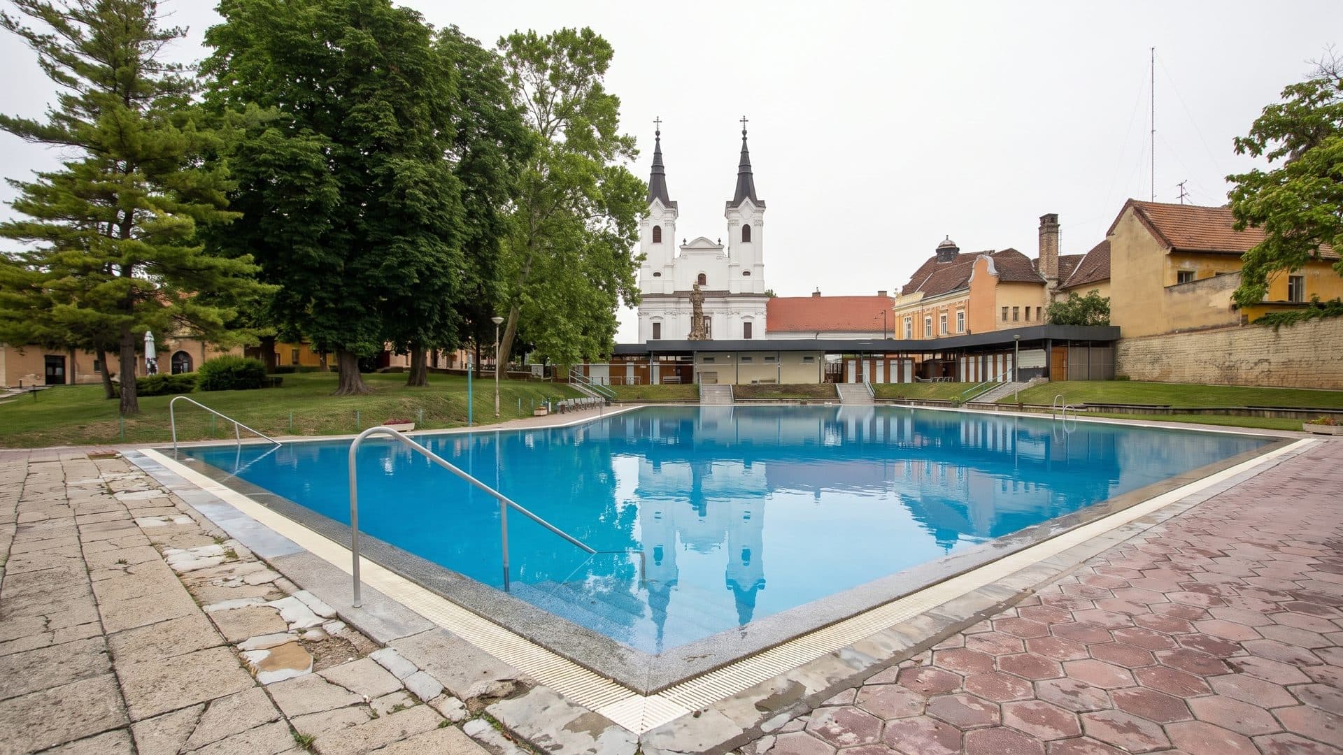 The outdoor pool of the Vac town baths, with the twin towers of the church rising beyond it