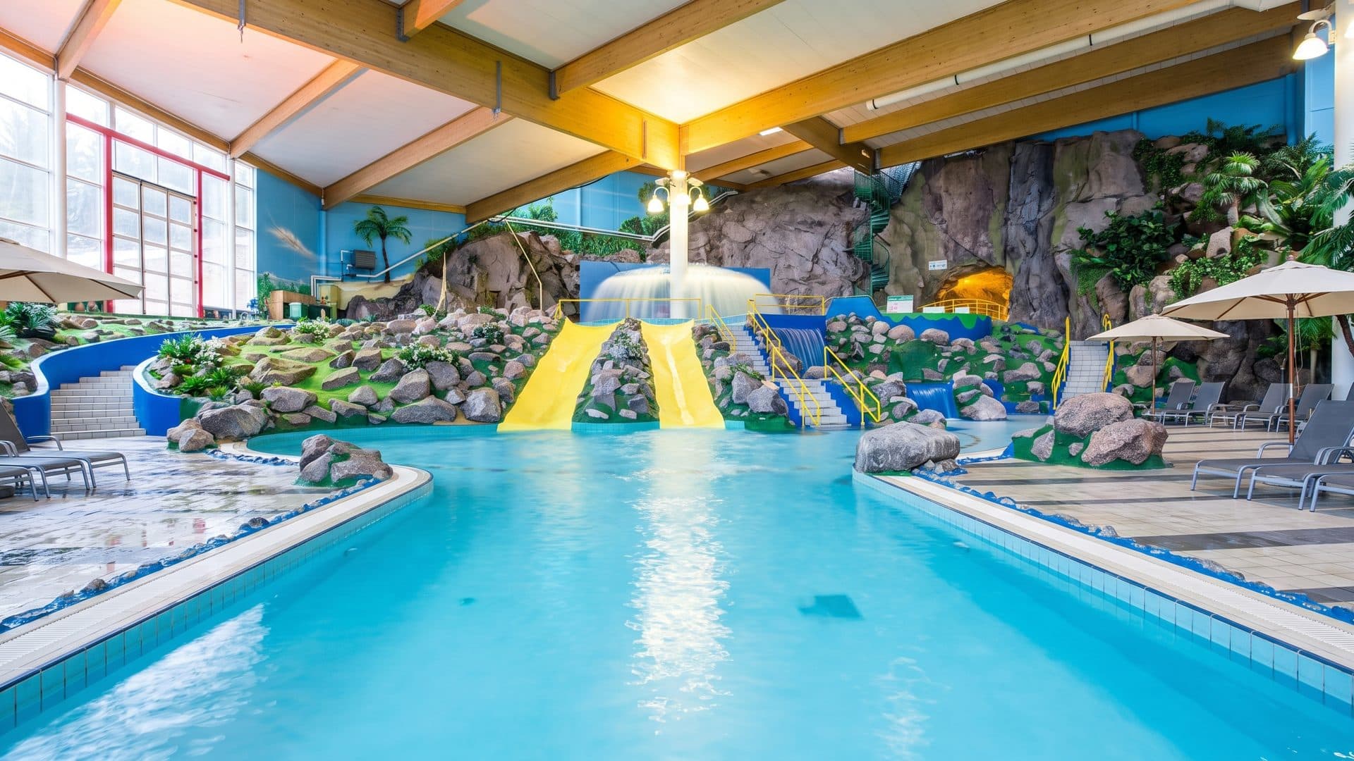 The indoor pools at Serena under a timber ceiling, with rock-built slides running down into turquoise water