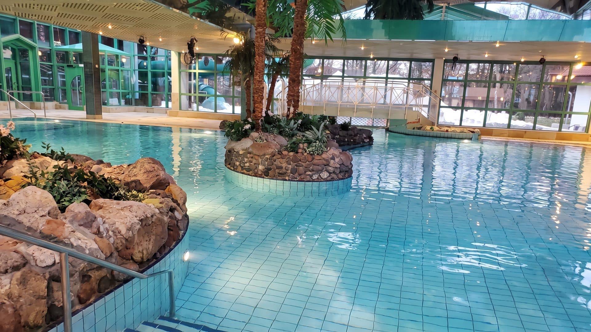 The thermal pool of the Weidener Thermenwelt around its planted rock island by the glazed wall