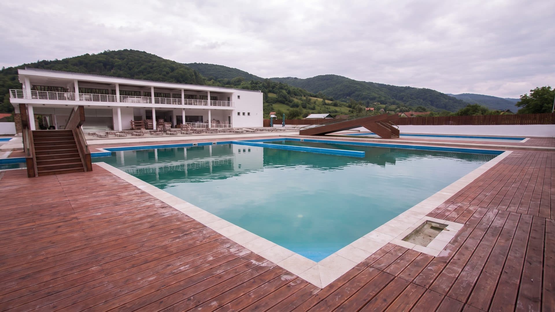 The outdoor pool of the Praid wellness centre with the building and hills behind