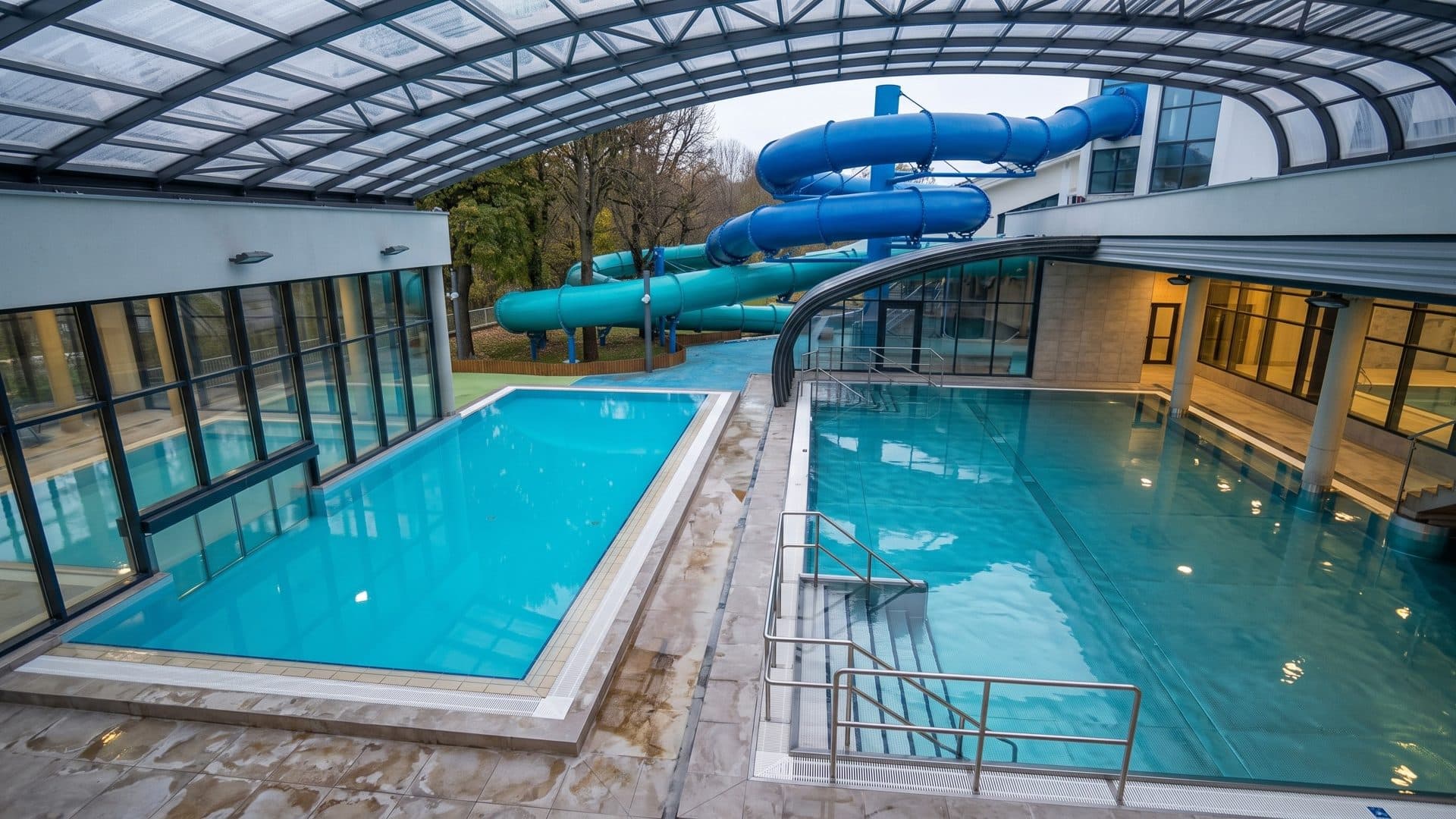Pools of Wodny Park Warszawianka under a retractable glass roof, blue slides outside