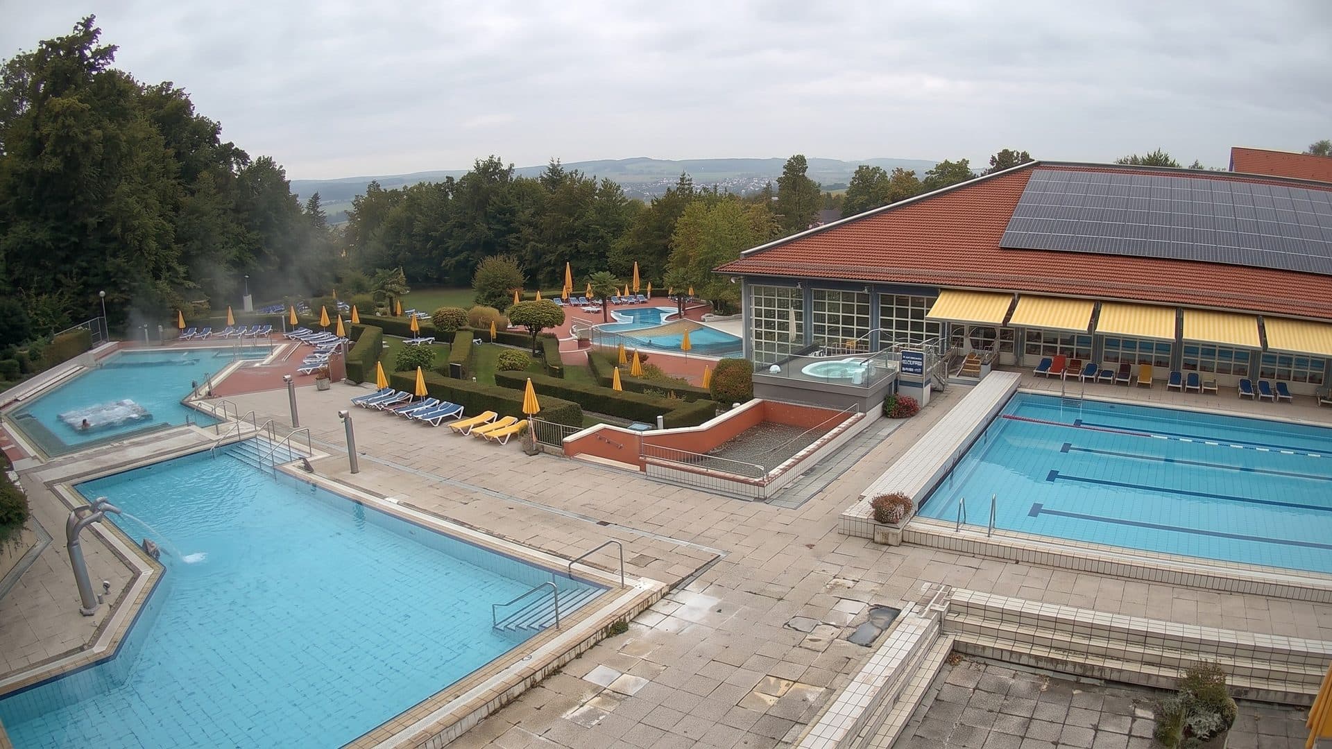 Outdoor pools of the Wohlfuhl-Therme in Bad Griesbach seen from above, beside the red-roofed bath hall